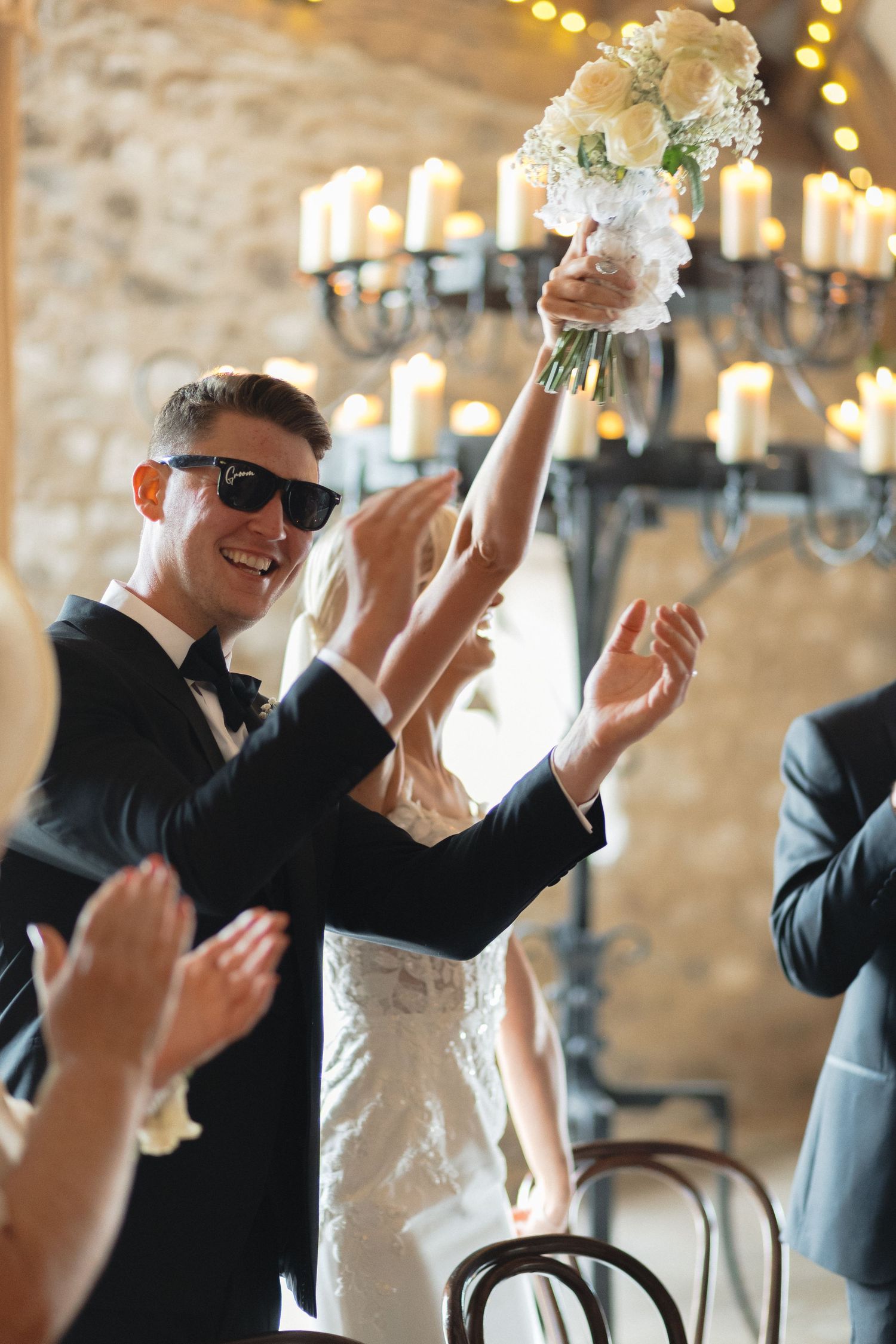 Celebratory moment at a wedding reception with guests raising hands in joy.
