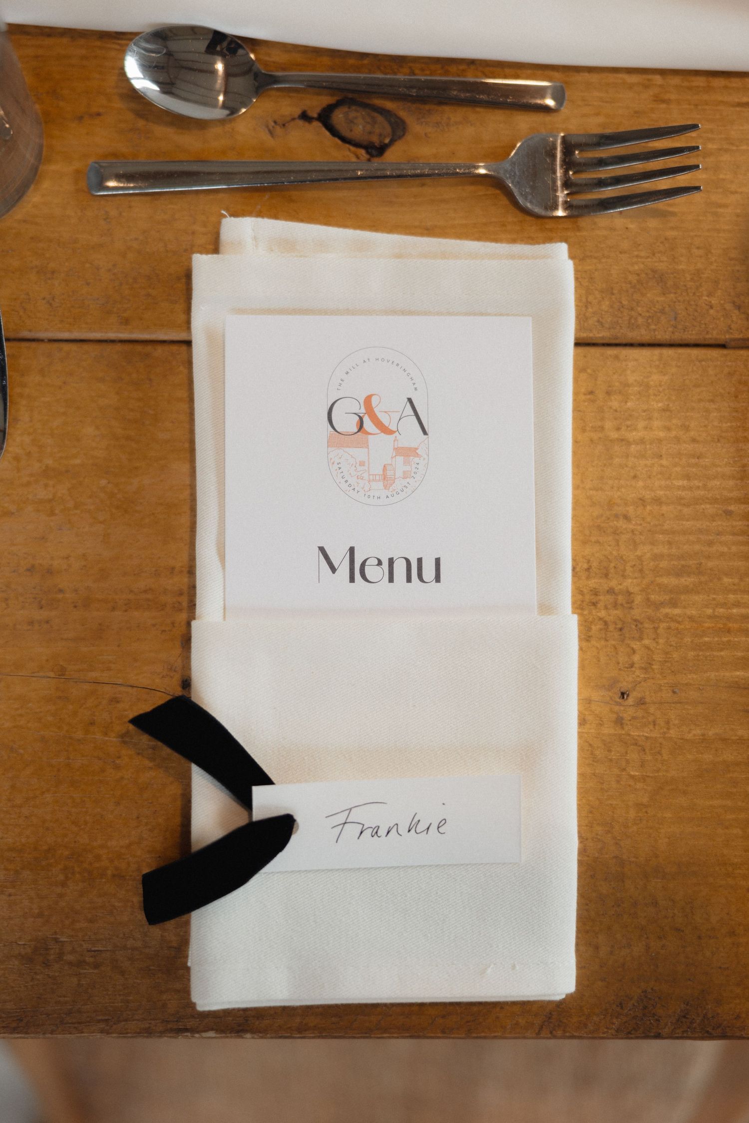 Wedding menu cards with black ribbon accents placed on wooden tables.