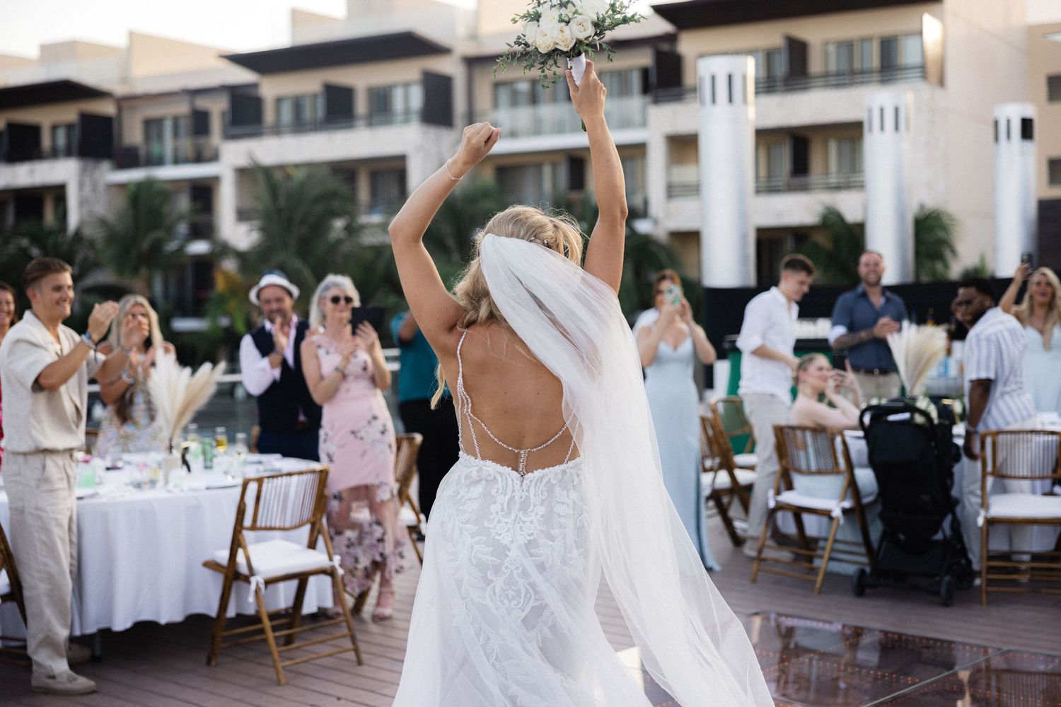 Outdoor wedding reception setup with white tables and chairs at a beachfront resort.