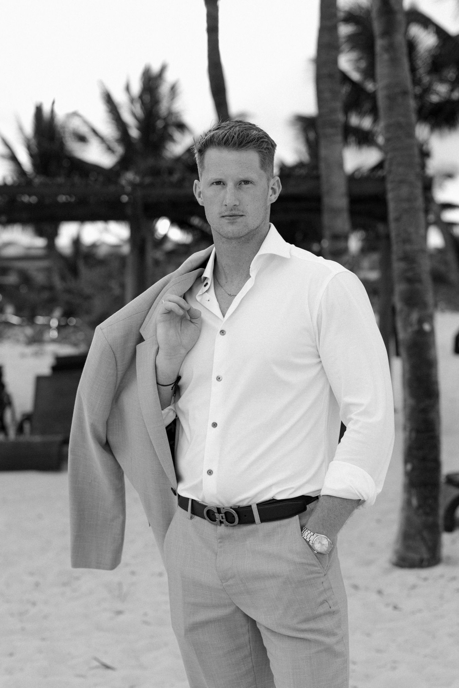 A series of black and white portraits showing someone in a white shirt and light colored pants on a tropical beach.