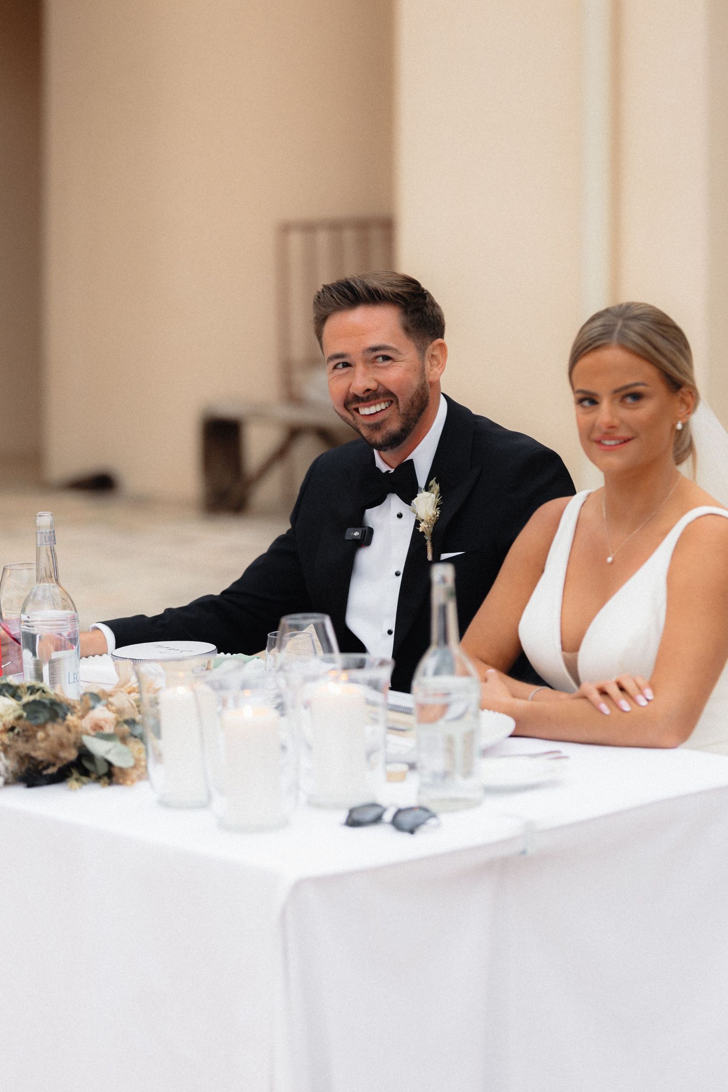 Wedding party seated at a formal white dining table during reception celebration.