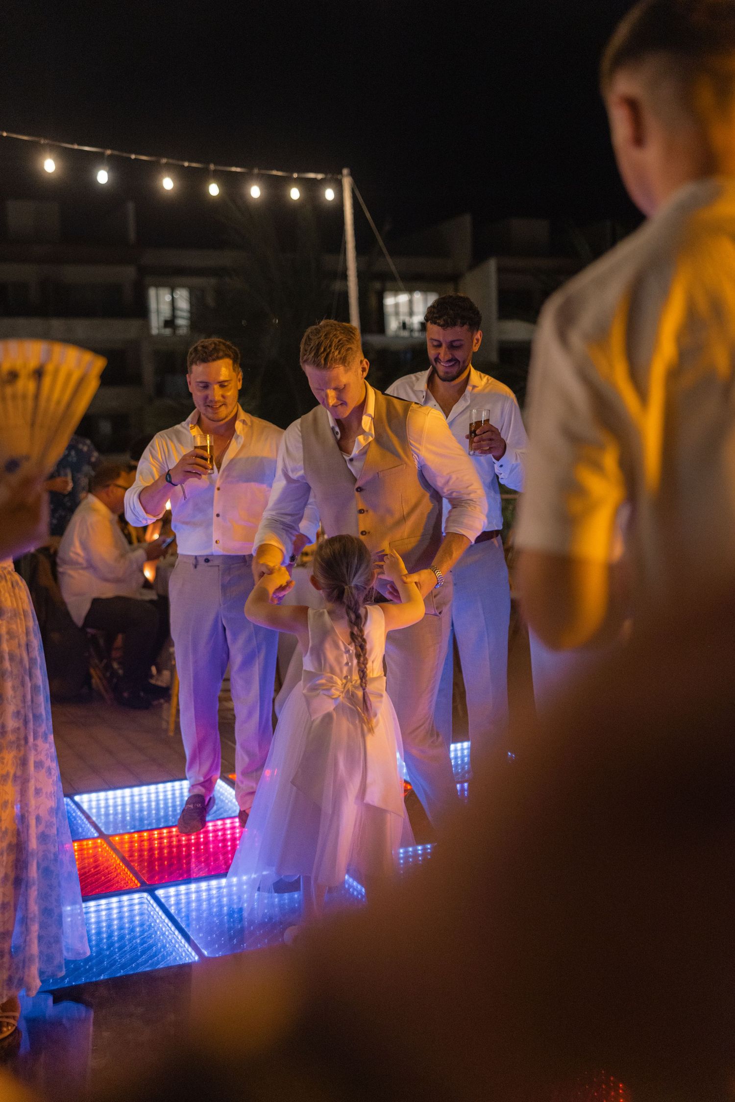 Wedding party gathered around an illuminated LED dance floor during nighttime celebration.