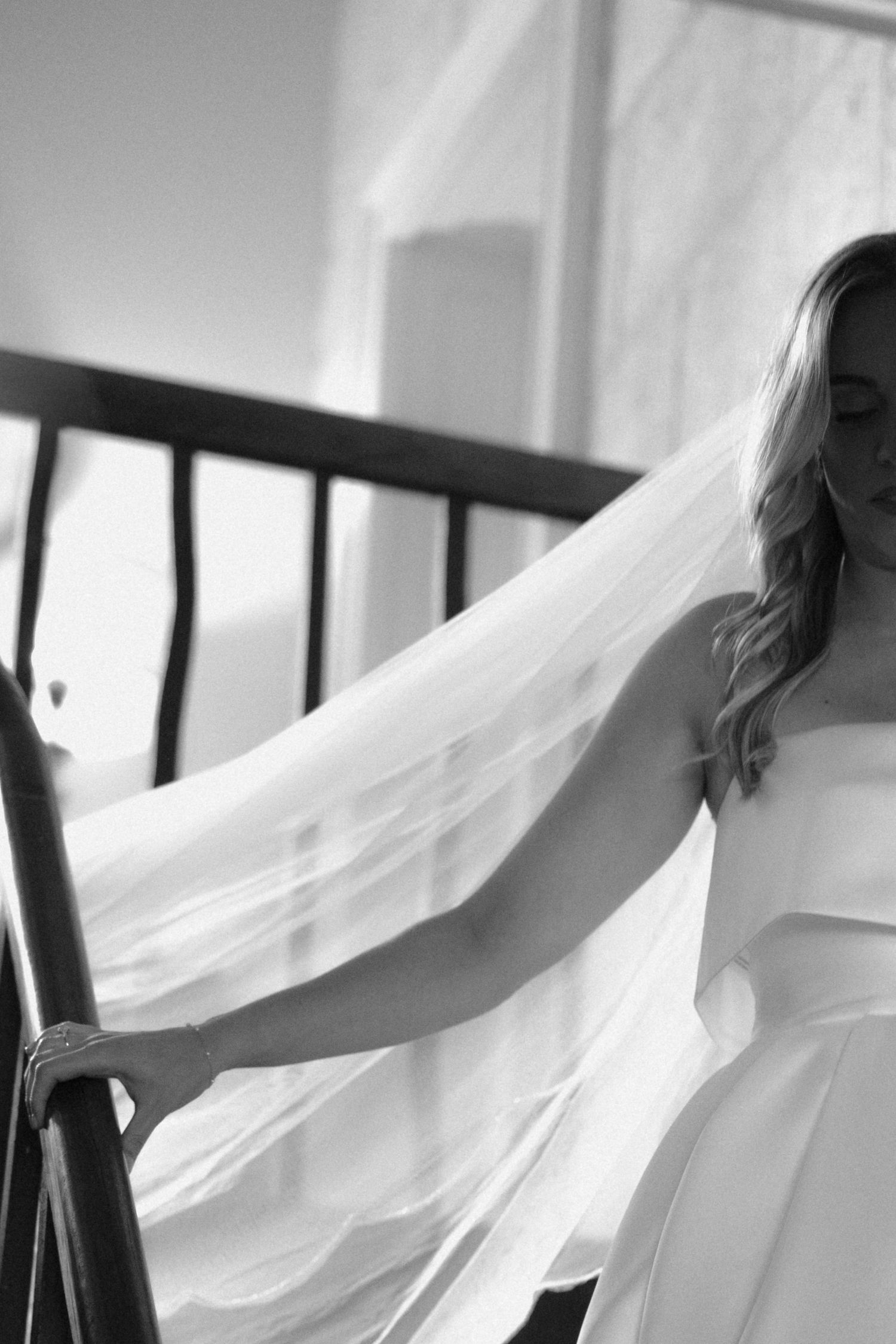 Black and white artistic photo of flowing white wedding veil fabric against a window.