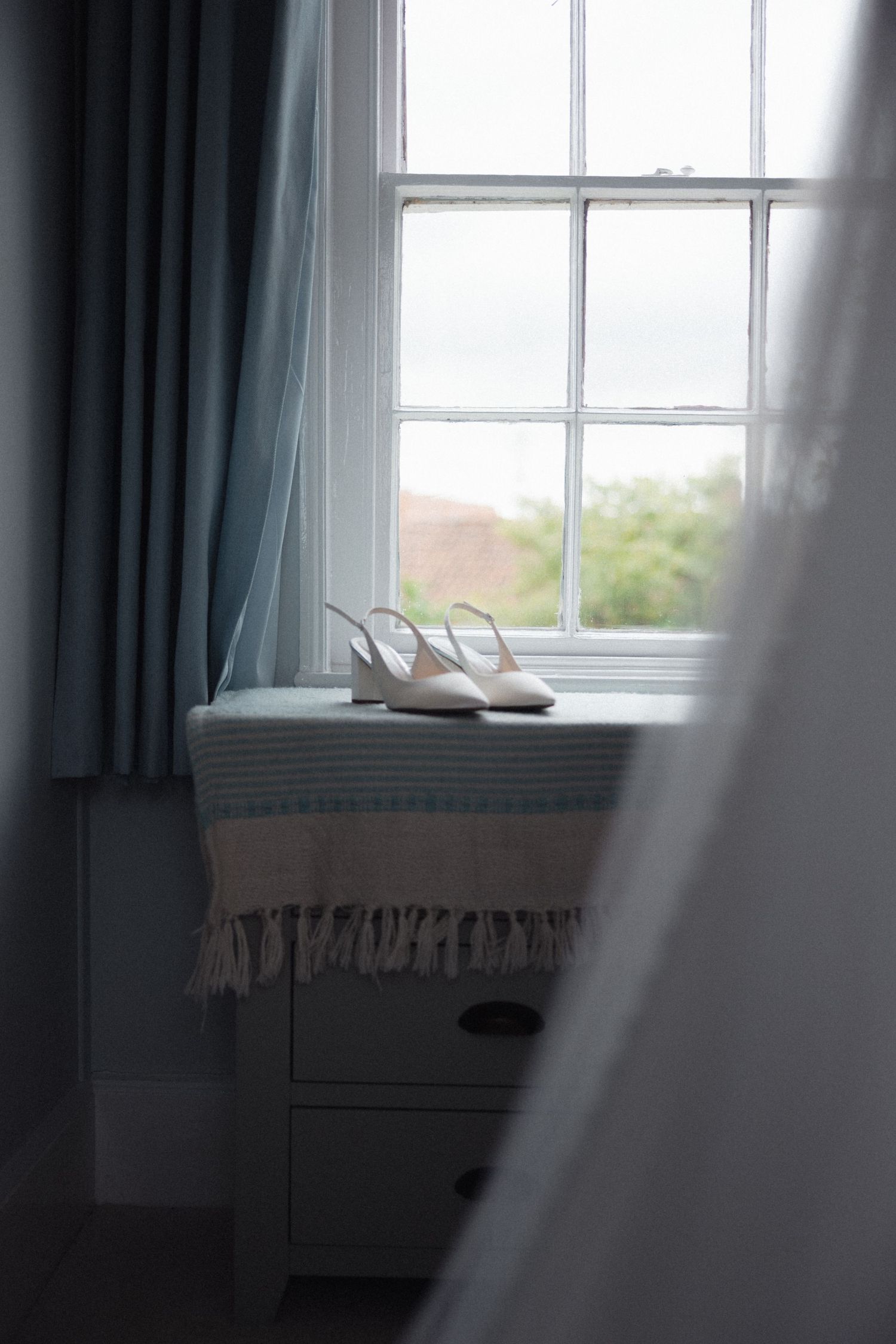Sunlit window with sheer curtains in a serene bedroom setting.