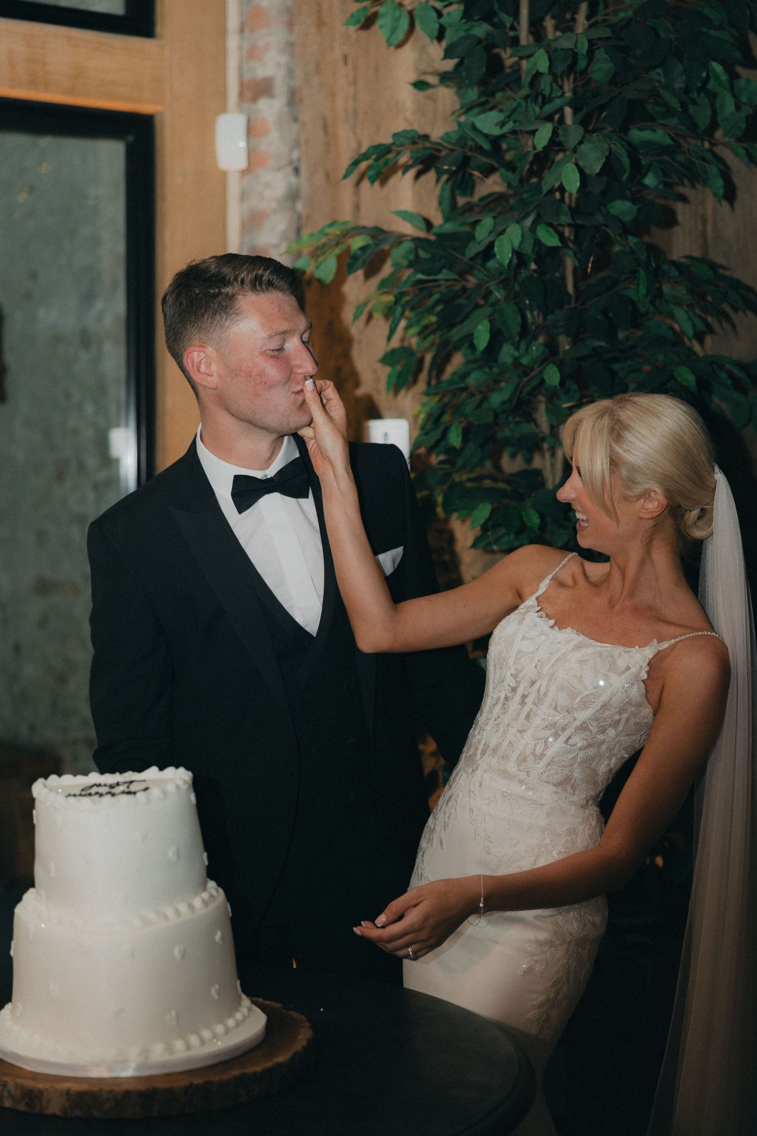 The bride playfully smears cake on the groom's face during their wedding reception.