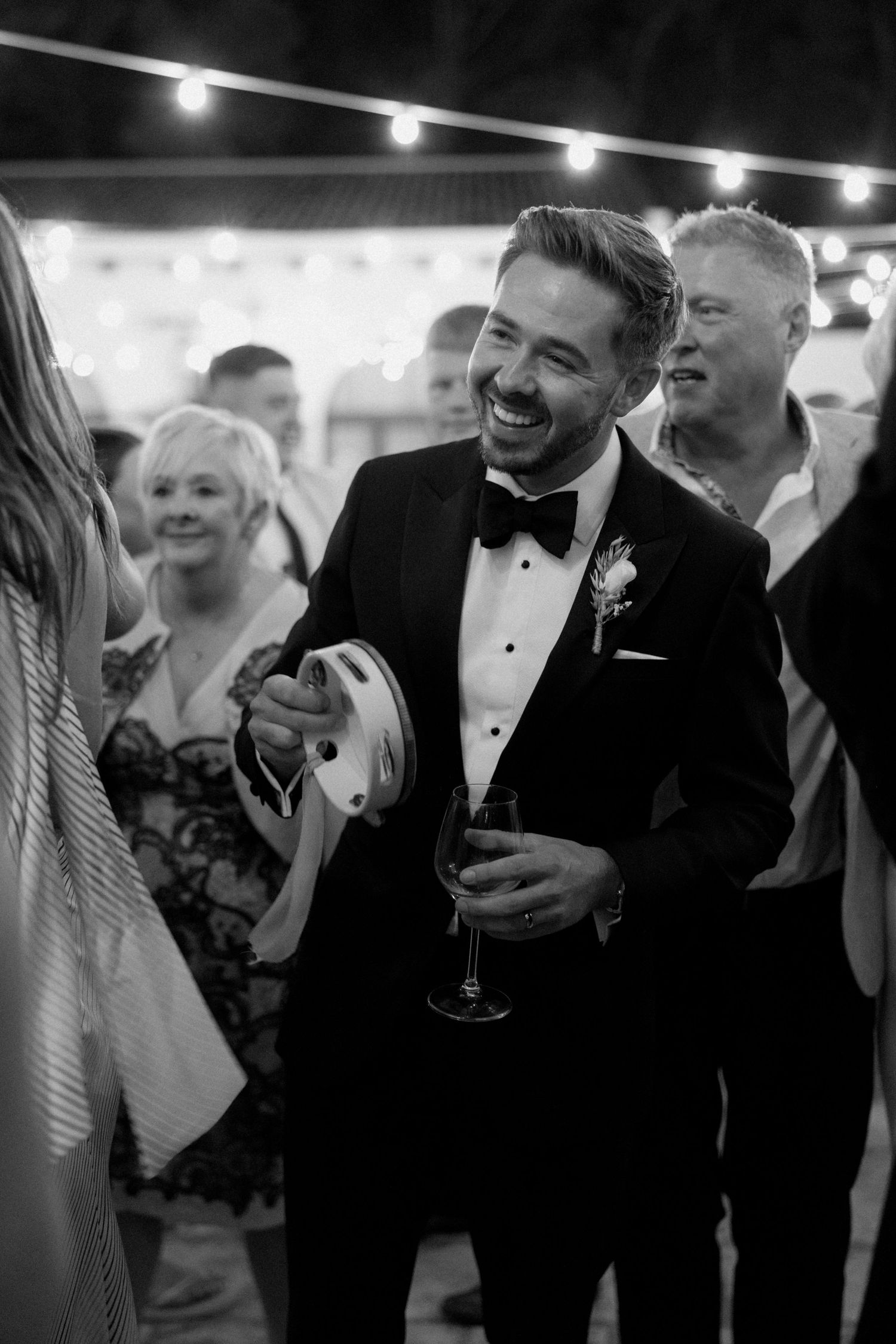 Wedding guests laughing and socializing at evening reception in formal attire.