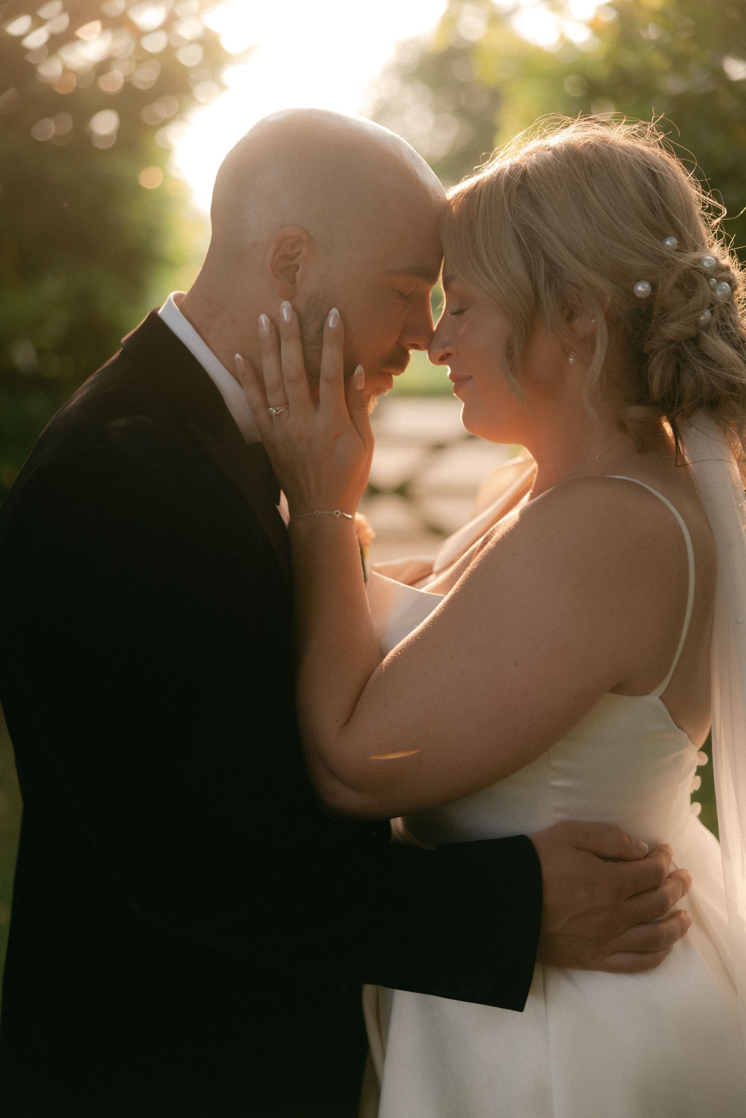 Intimate wedding couple silhouettes against sunset bokeh background.