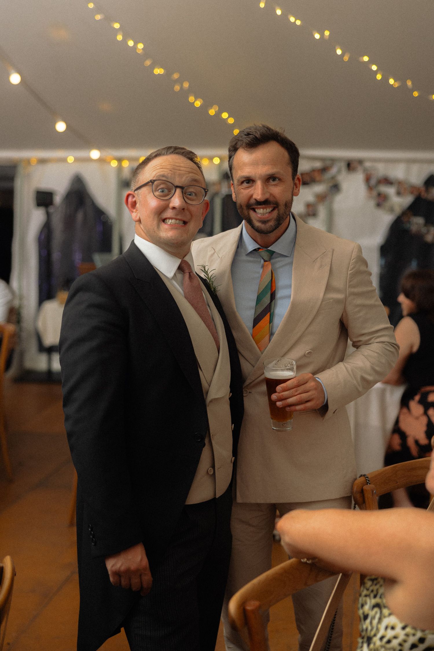 Wedding guests in formal attire share candid moments during an indoor reception.