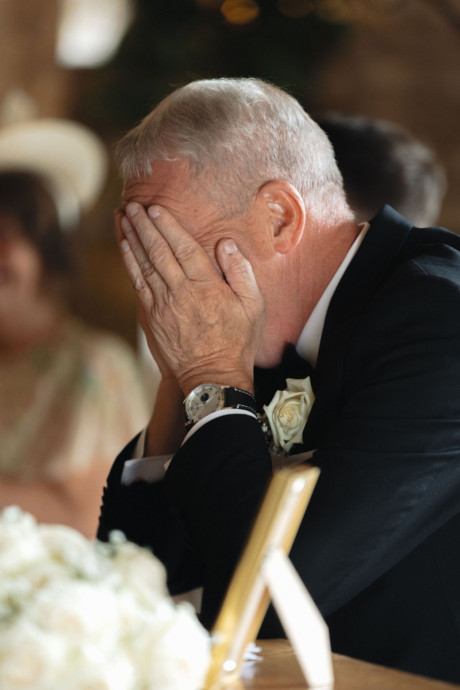 An emotional moment as a guest at a wedding covers his face with his hands while wearing a formal suit.