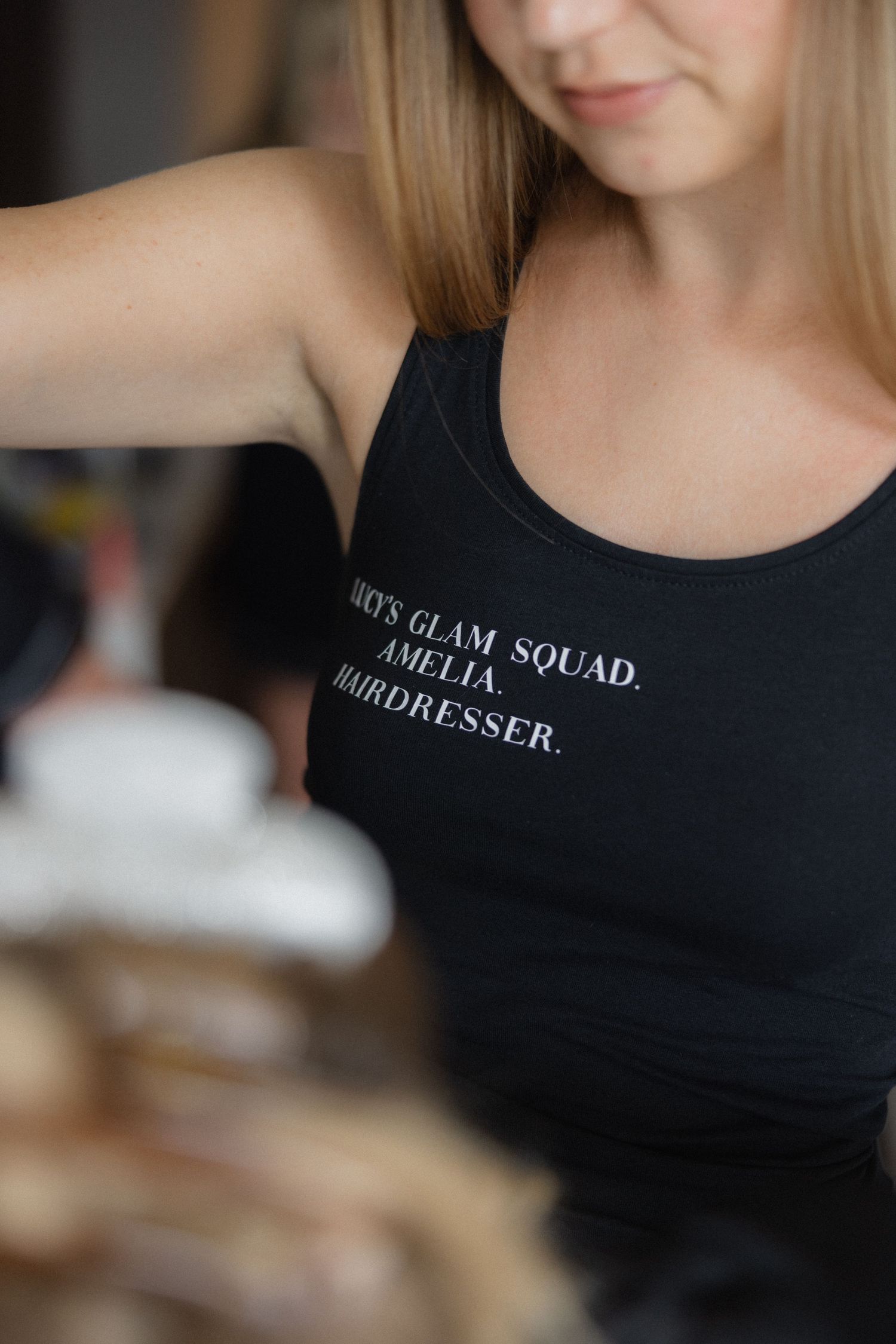 Close-up of black uniform shirt with text reading 'Glam Squad' in white lettering.