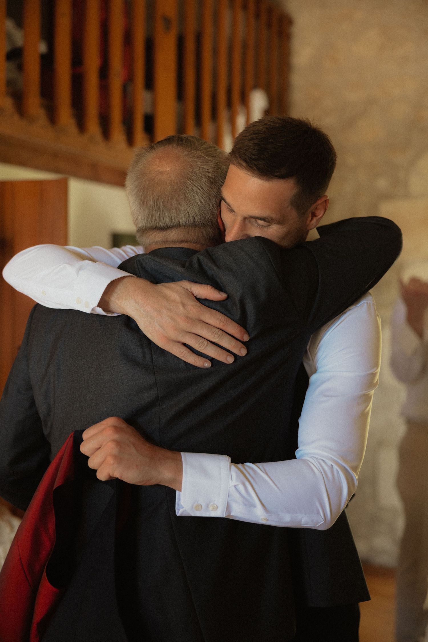 Emotional embrace between two people in formal attire.