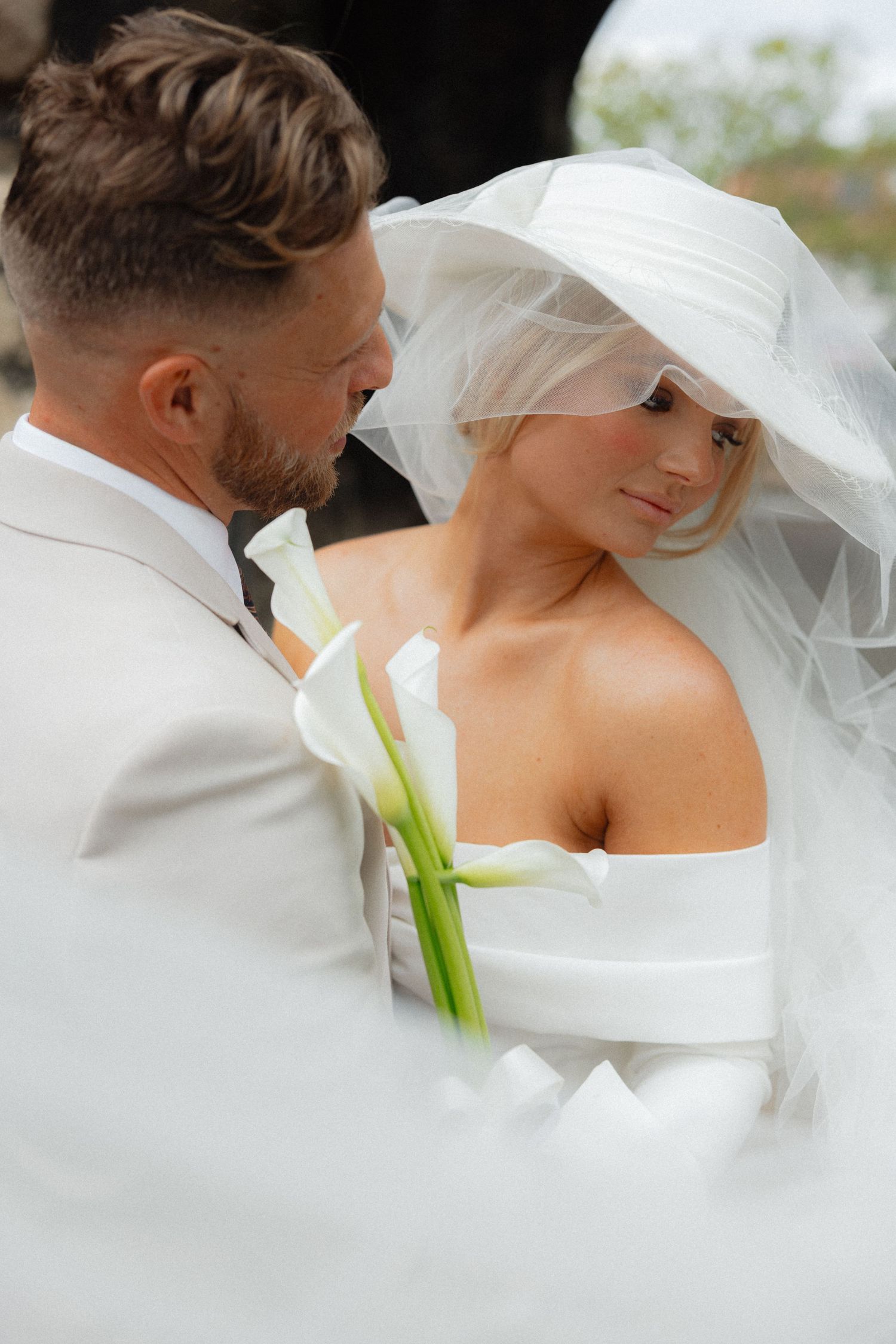 An intimate wedding portrait featuring a calla lily and flowing veil.