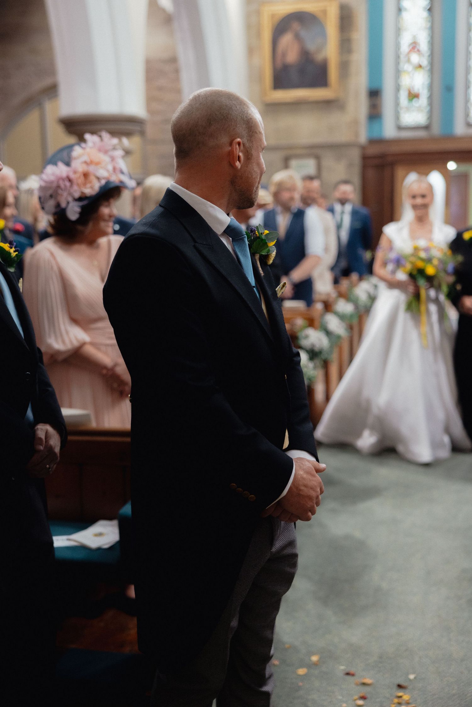 Wedding ceremony attendees gathered in a church with turquoise walls and traditional decor.