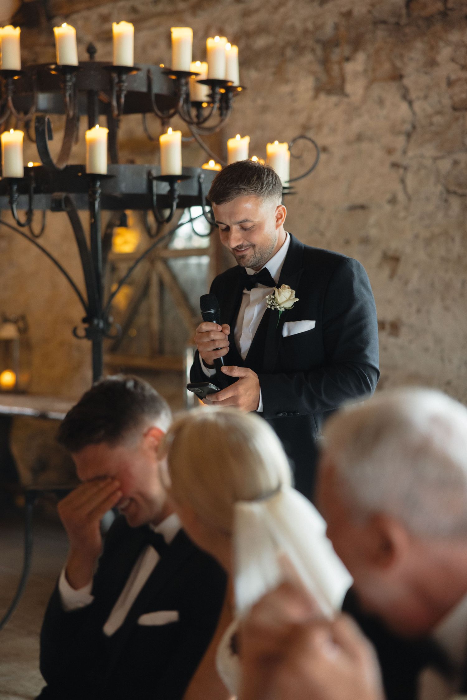 Emotional moments shared during speeches at a formal reception with stone walls and candlelight.