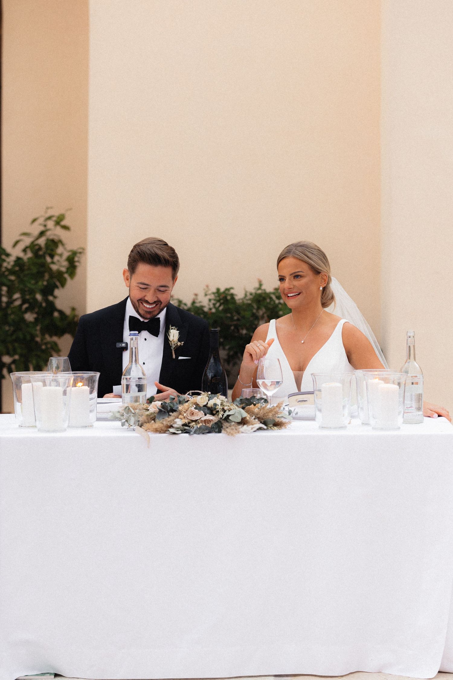 Wedding couple shares a laugh at their reception head table.