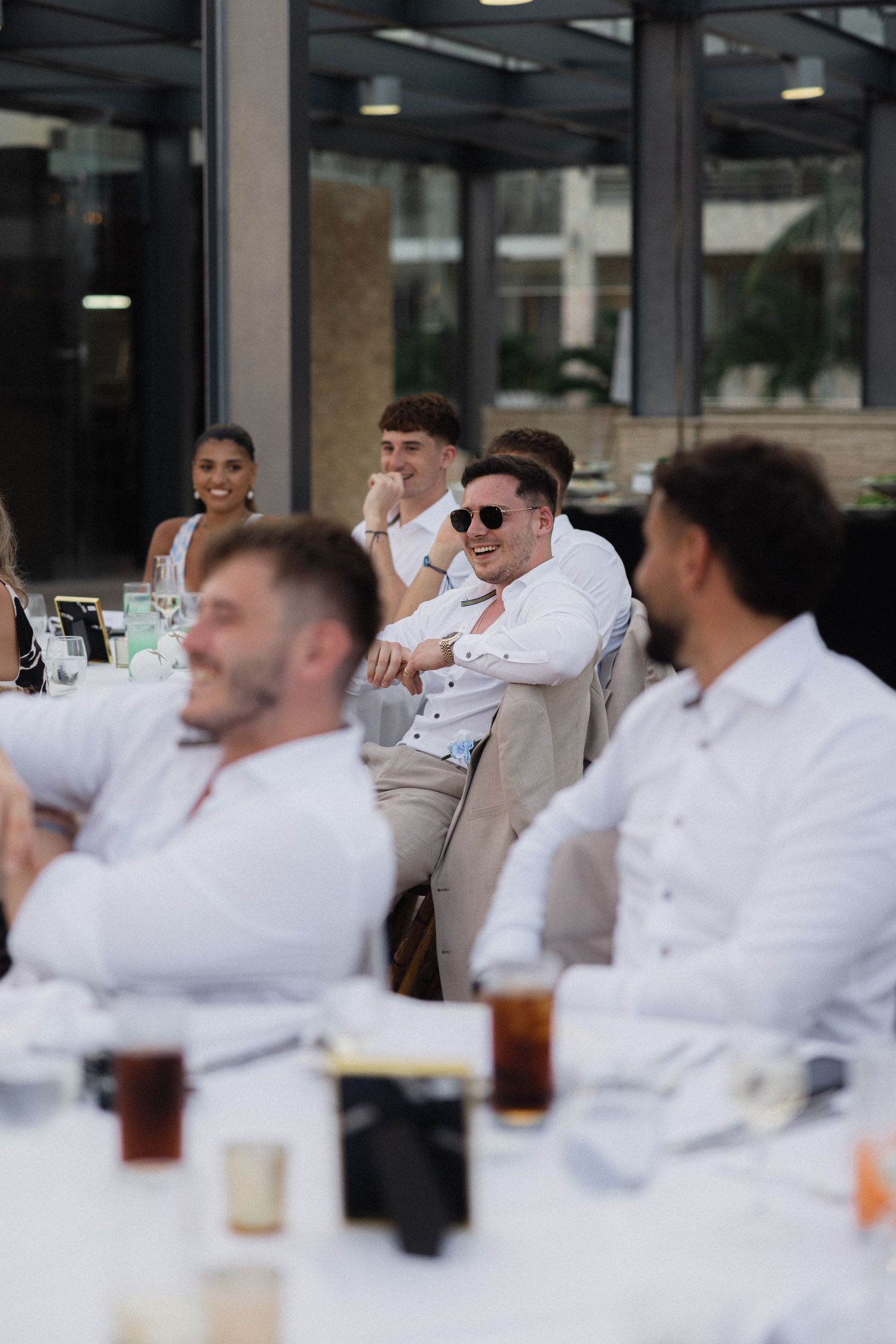 Wedding party relaxing at outdoor reception venue in coordinated white attire.