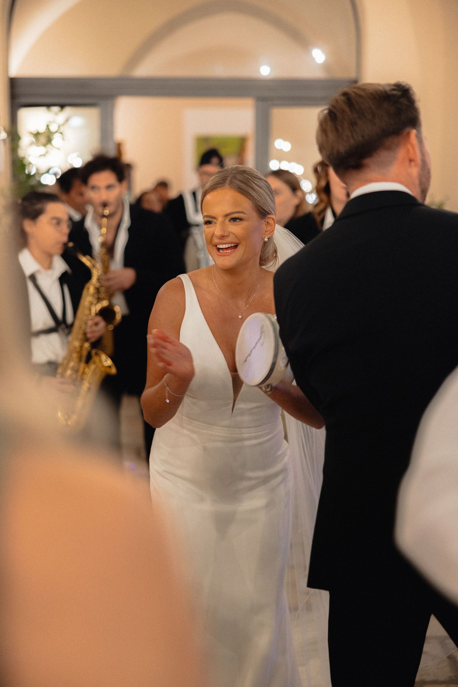 Wedding celebration with guests dancing and mingling in a warmly lit indoor venue.