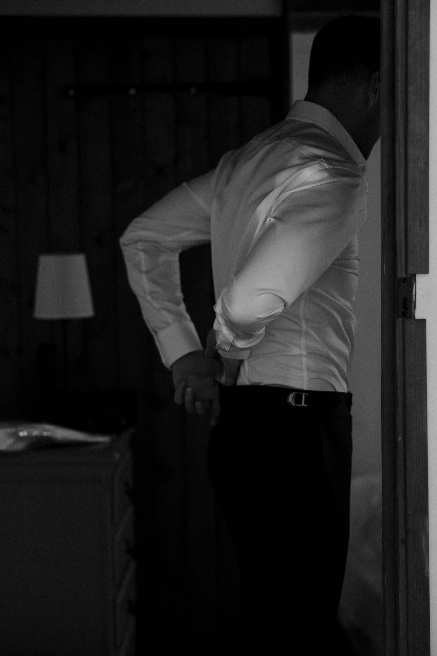 Person adjusting formal white shirt in dim lighting.