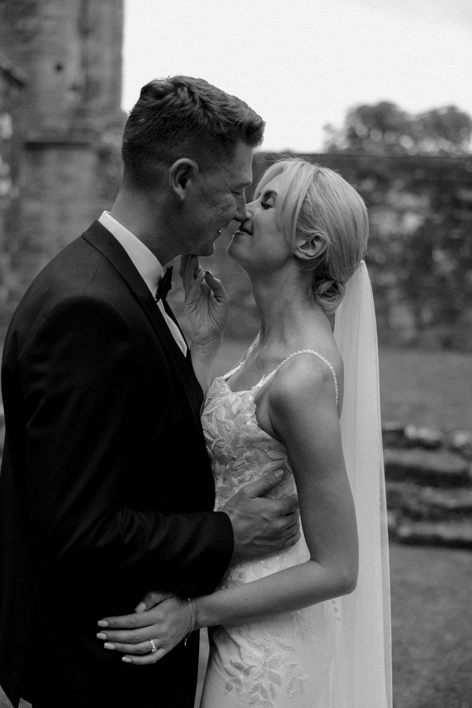 Intimate black and white portrait of couple sharing romantic moment by stone ruins.