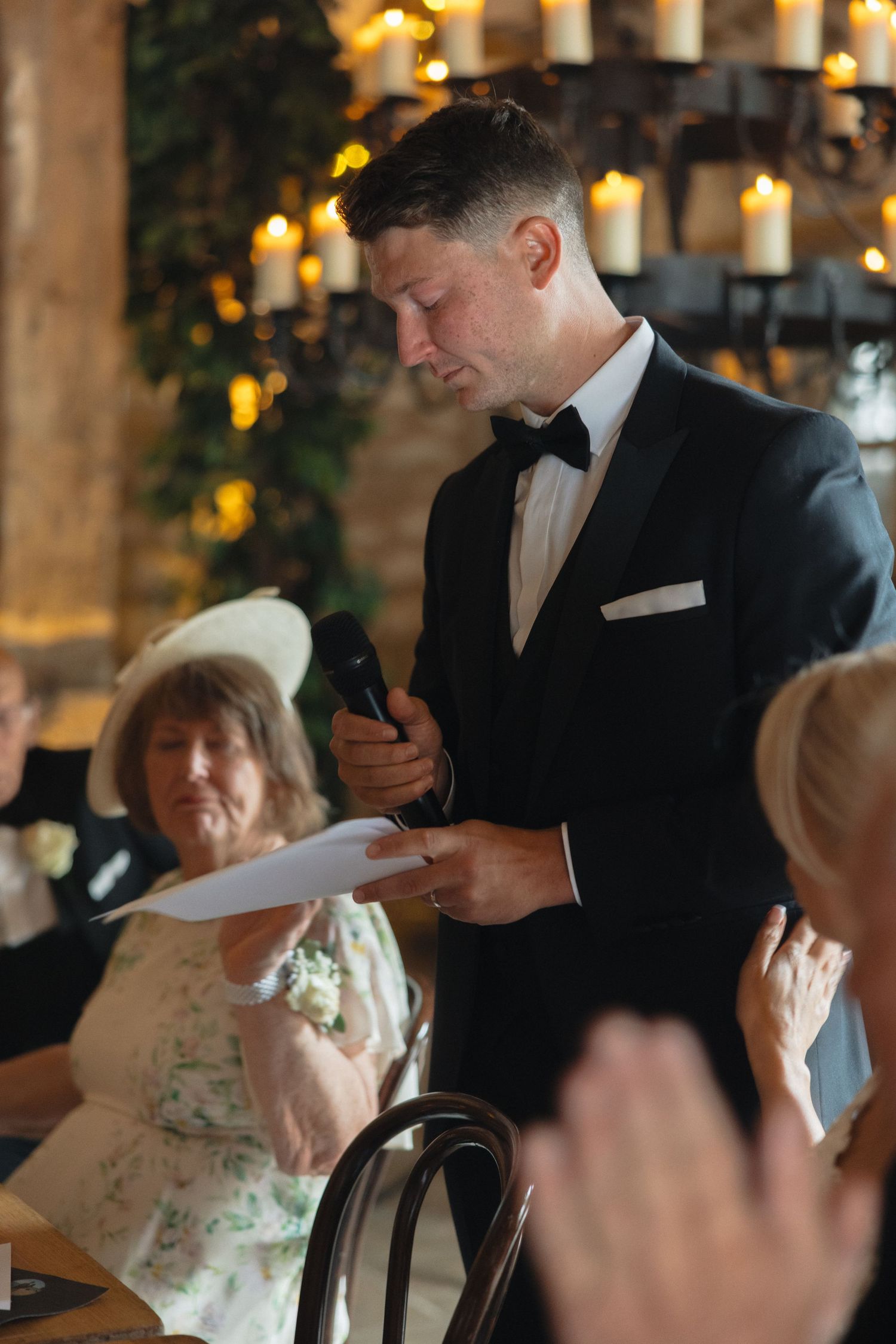 A speaker delivers remarks at an elegant reception while guests listen attentively.