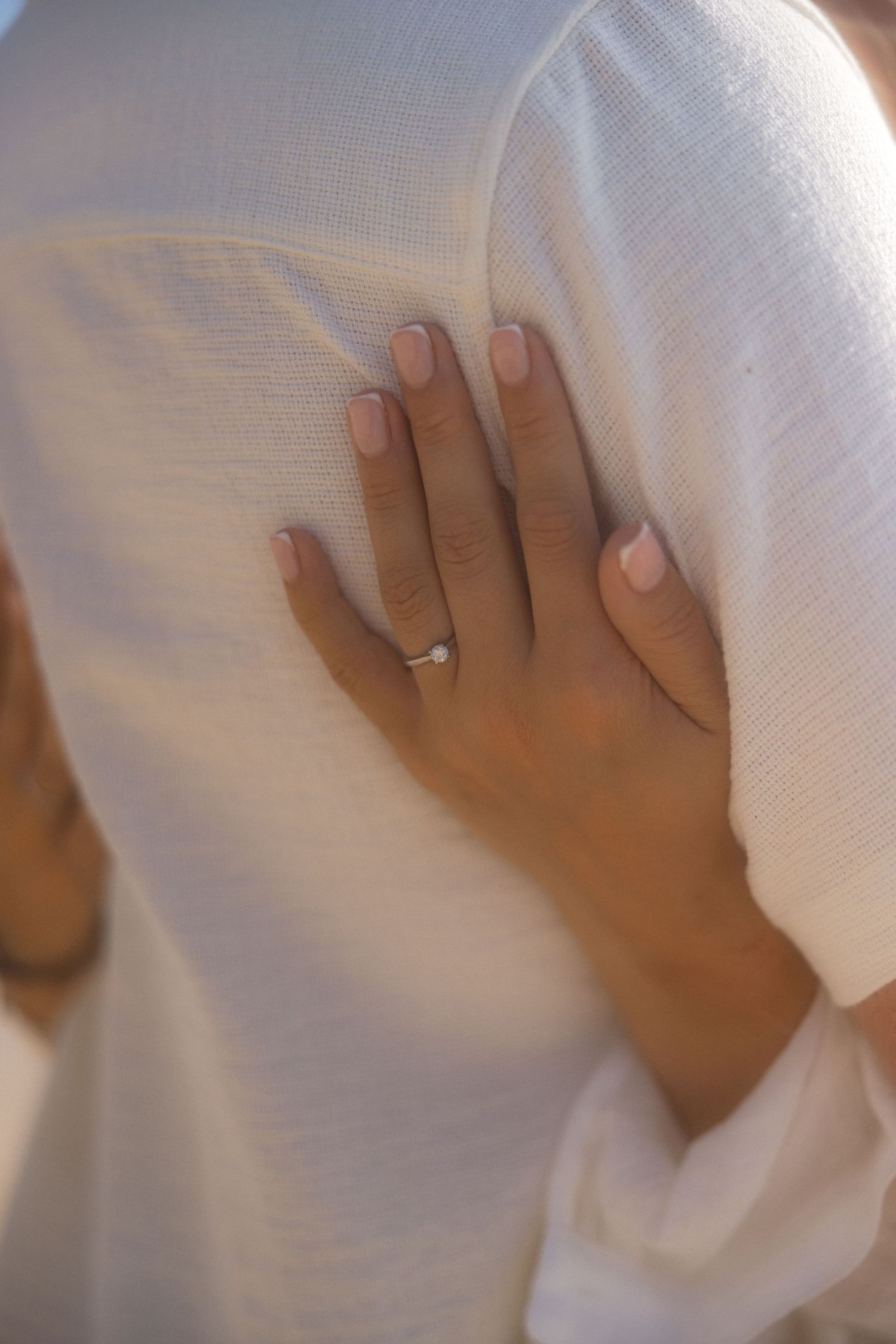 Close-up shot of hands gently placed on white fabric, showing tender affection.