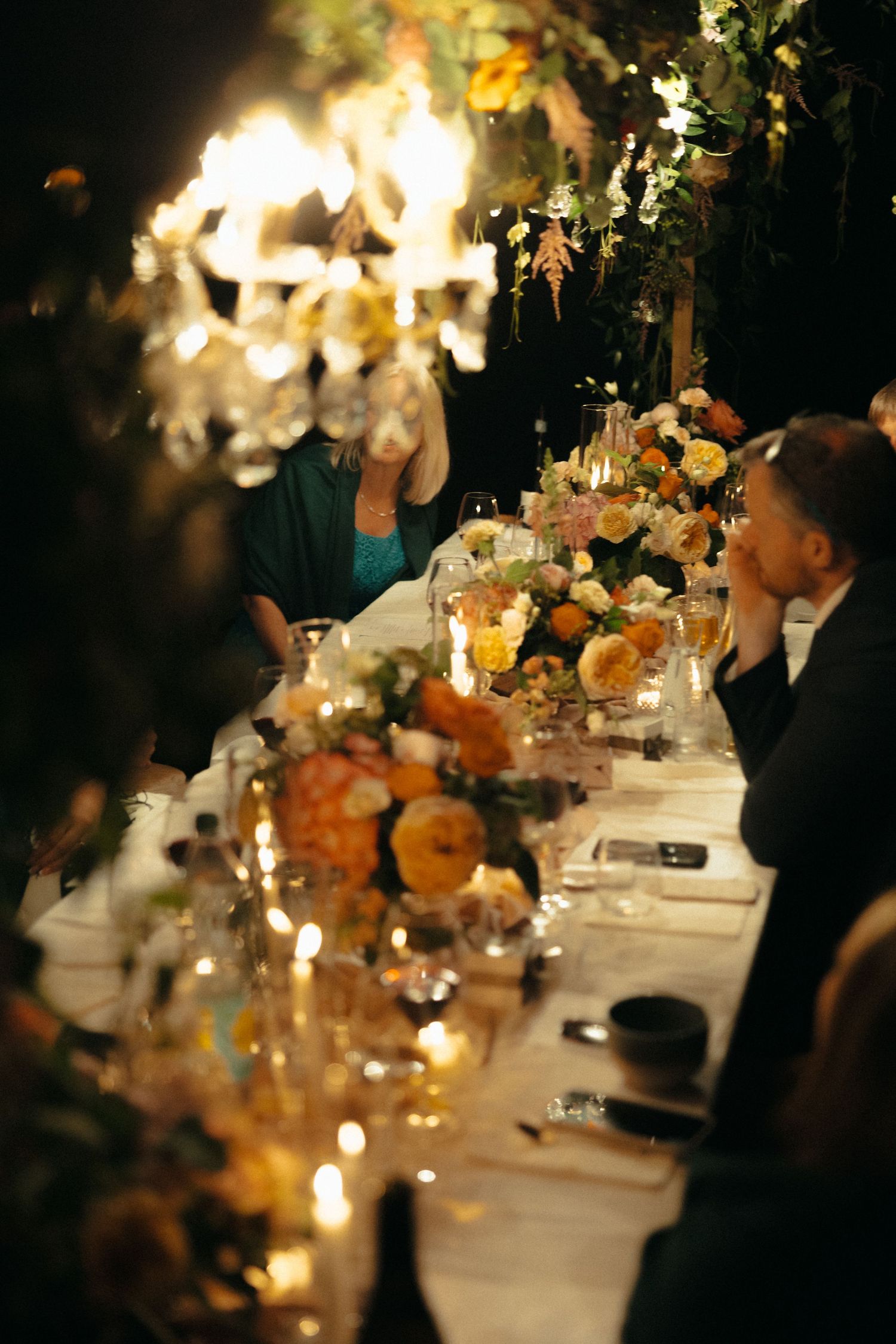 A romantic candlelit wedding reception table with soft focus floral arrangements.