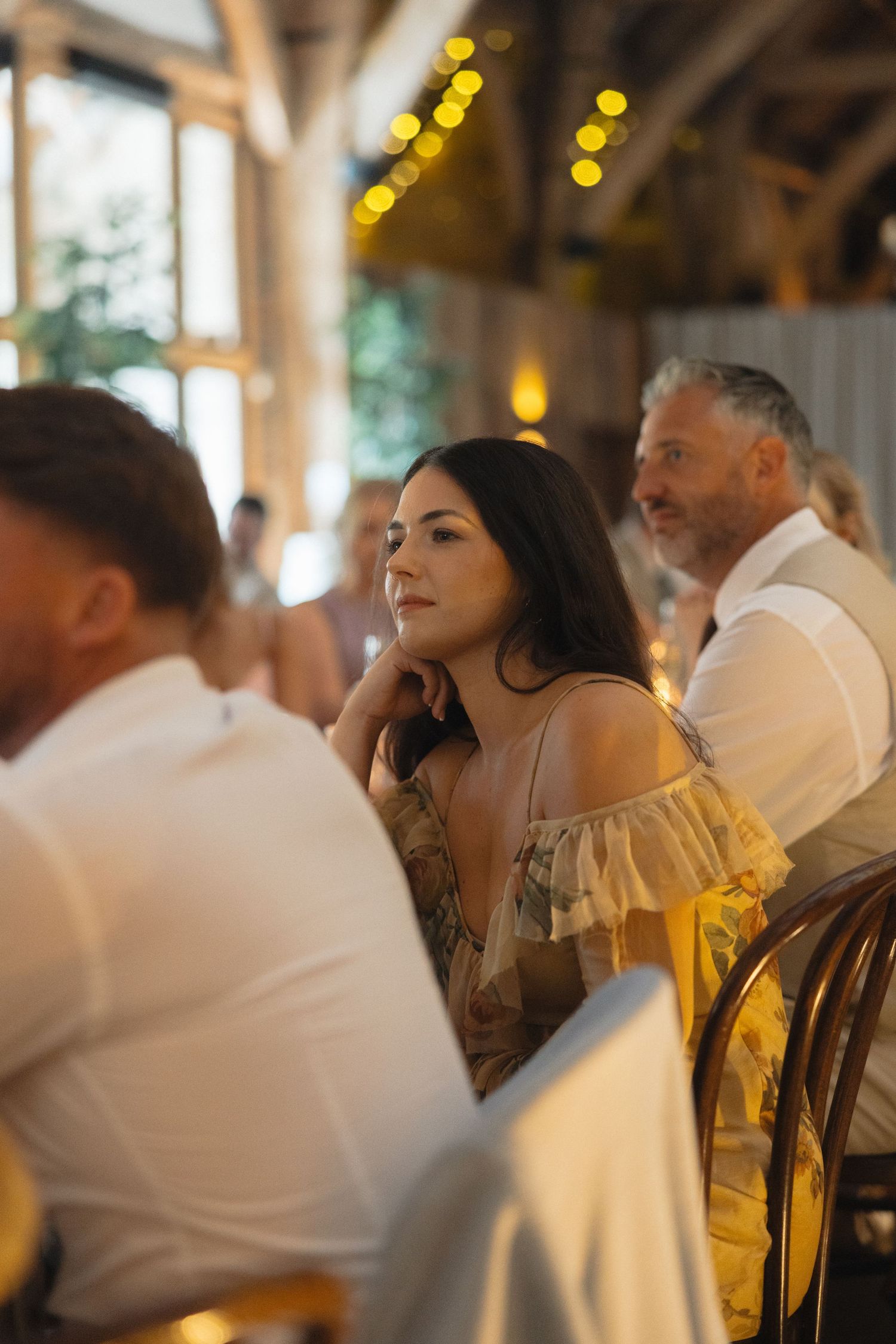 Wedding guests enjoy an intimate reception dinner with warm lighting and elegant table settings.