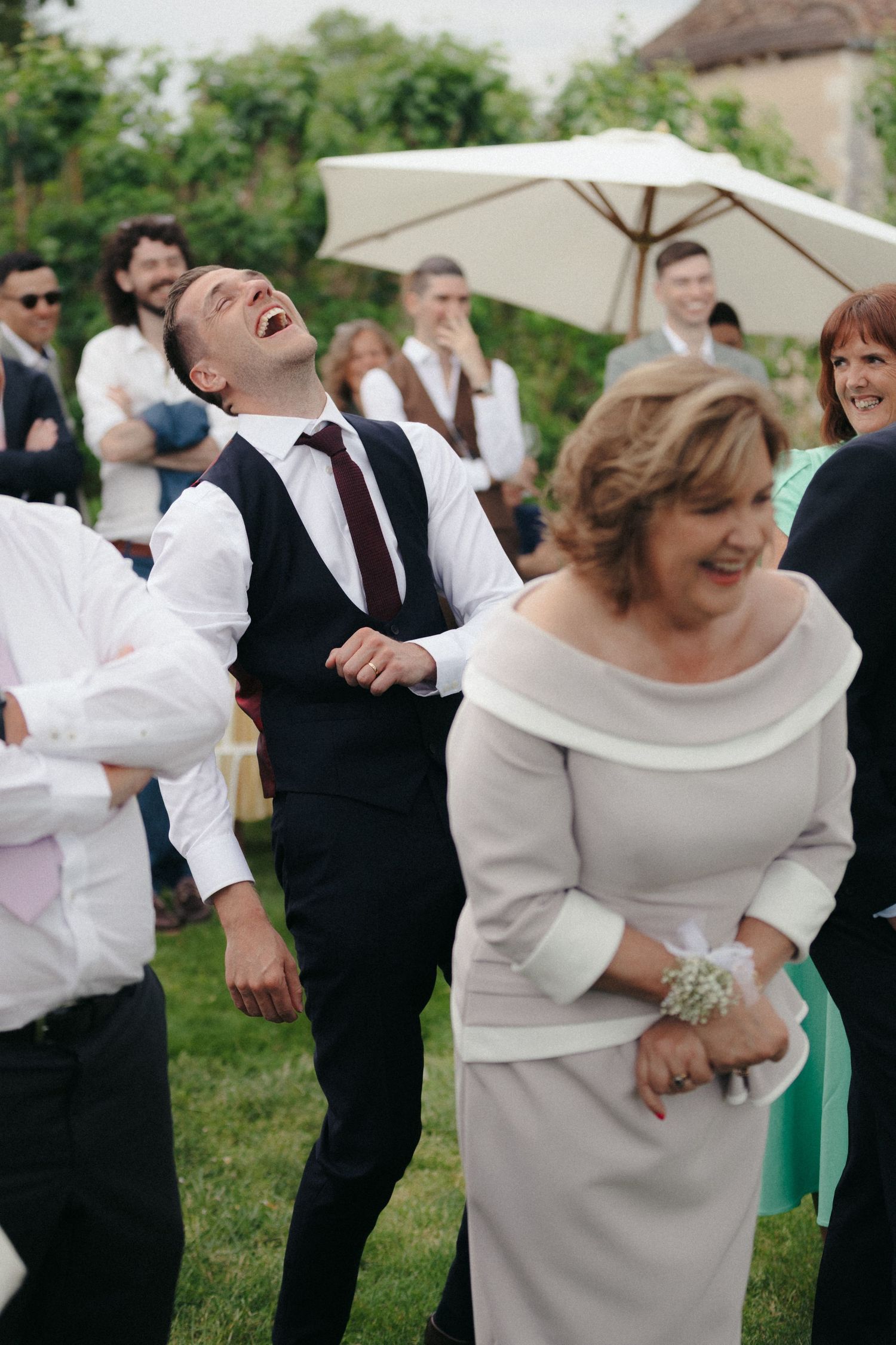 Joyful celebration at outdoor wedding with guests in formal wear dancing and laughing.