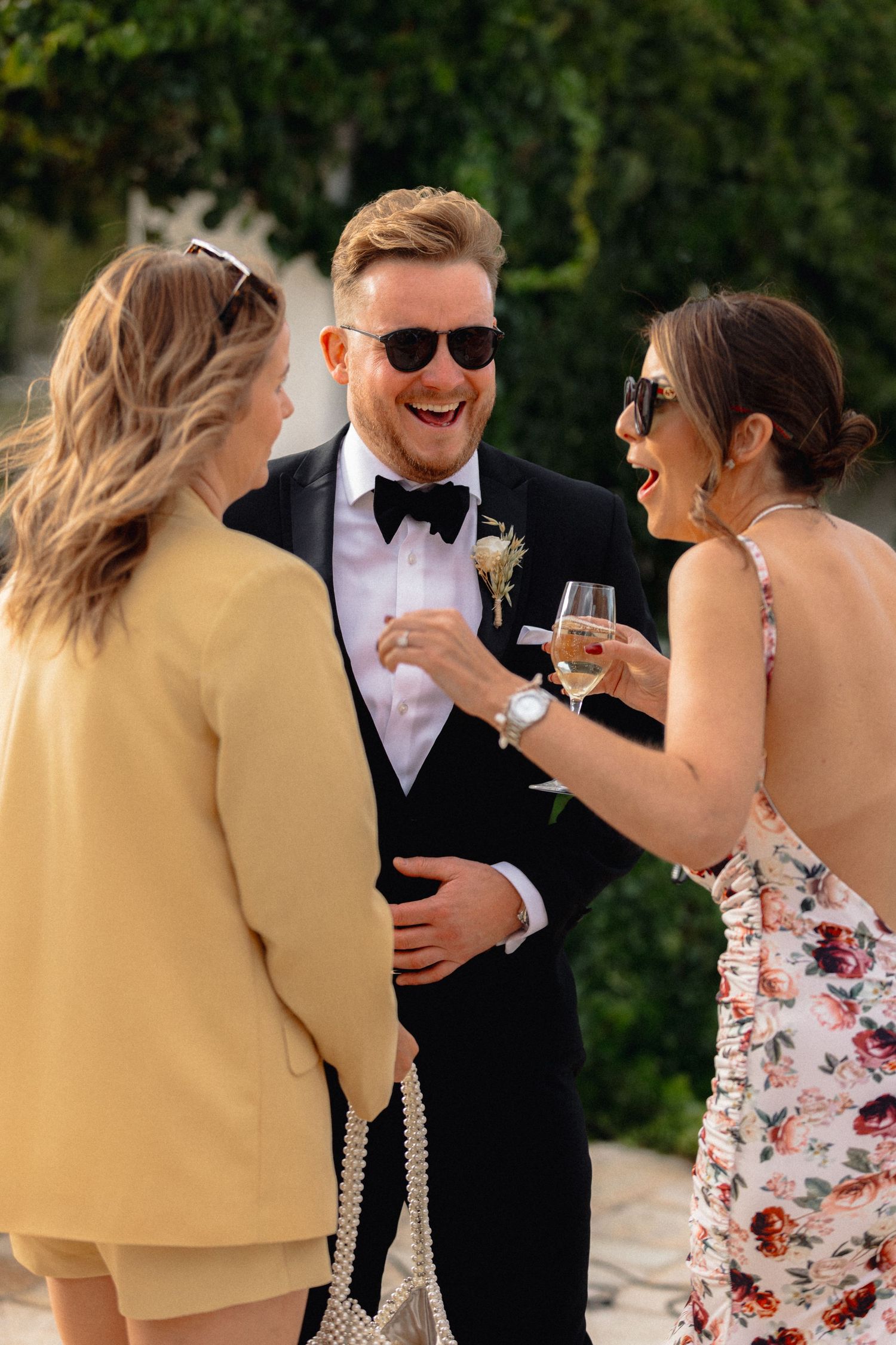 Wedding party shares laughs and champagne during outdoor celebration.