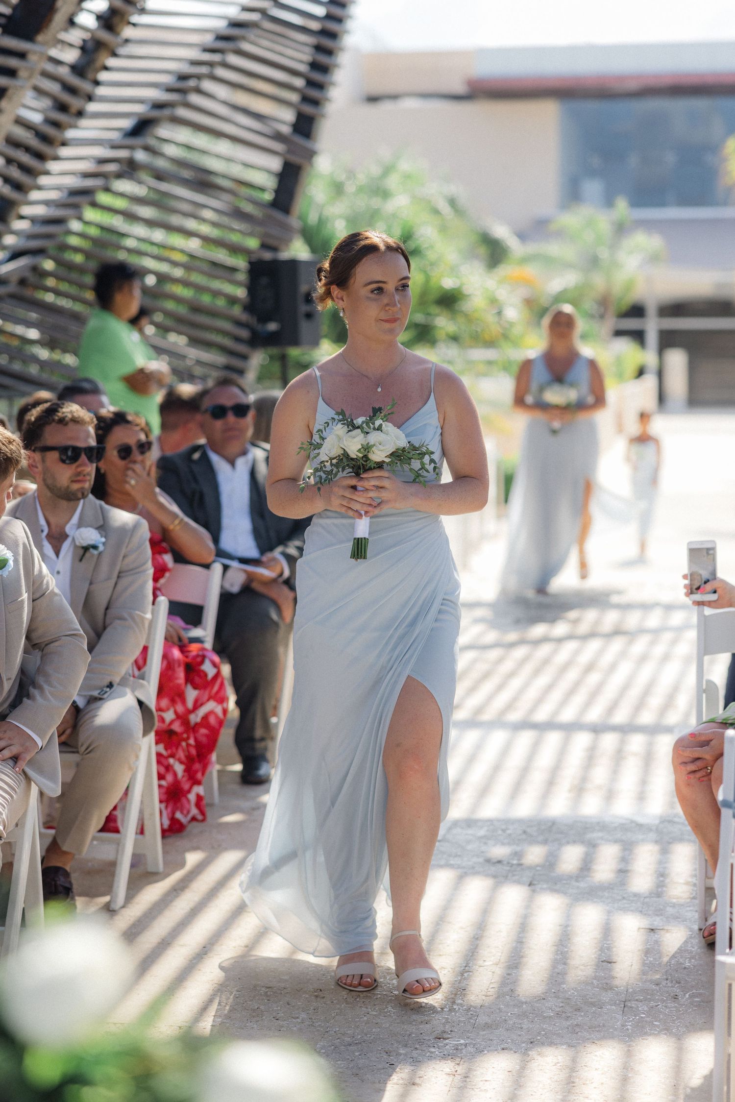 Wedding ceremony attendees under a pergola with dramatic striped lighting effects.