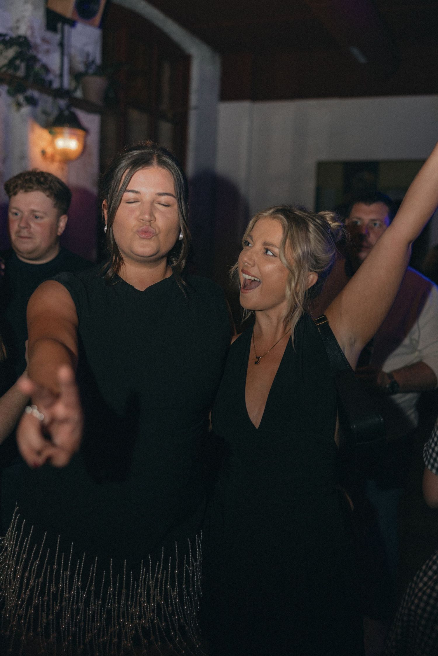 Party guests dancing and celebrating at a lively indoor event.