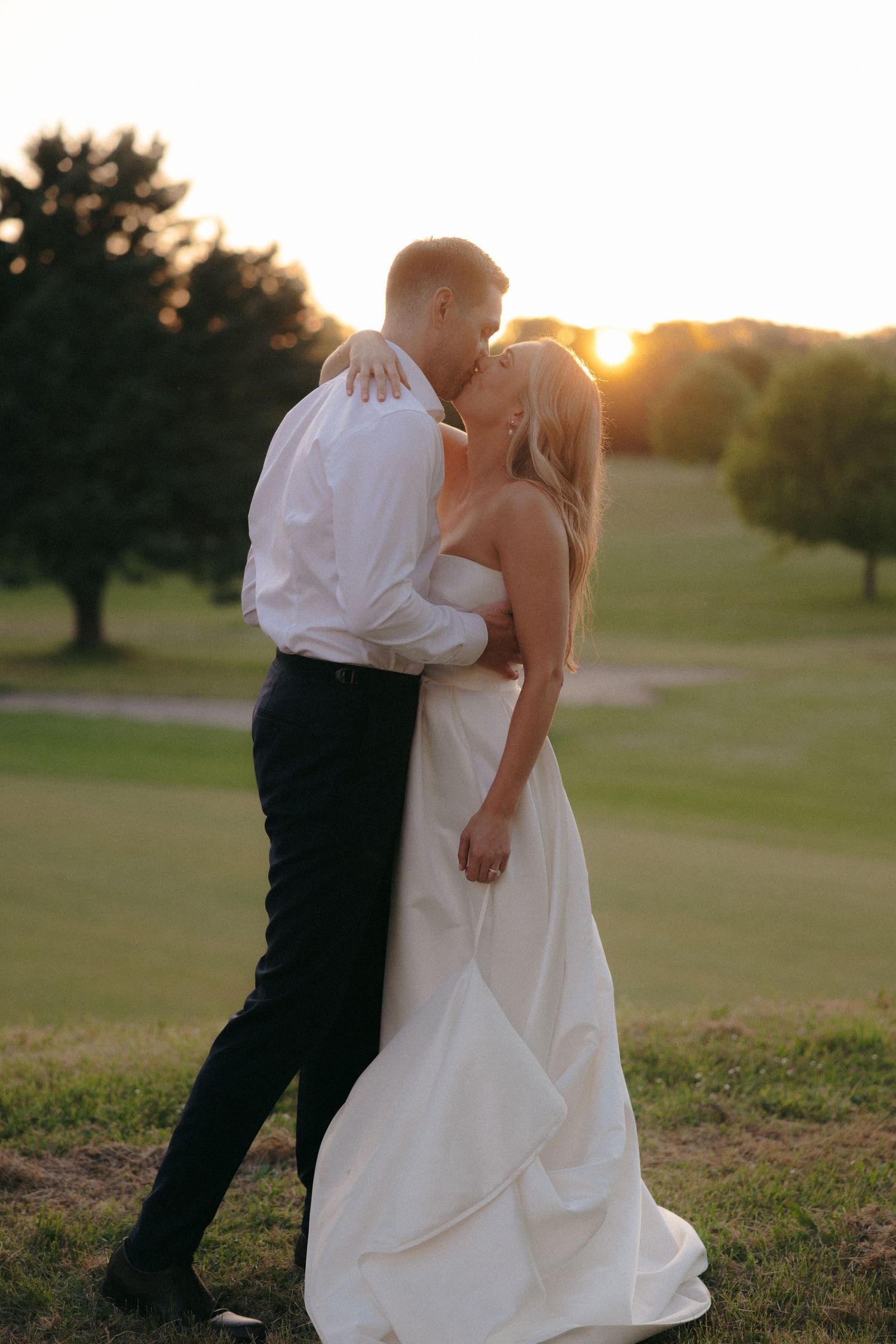 Couple embracing during golden hour on their wedding day in an outdoor setting.