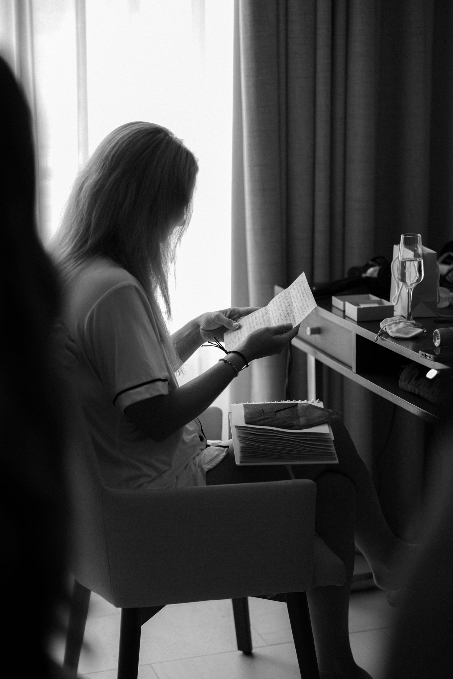 Silhouetted figure sitting by a window in a dark room getting ready.