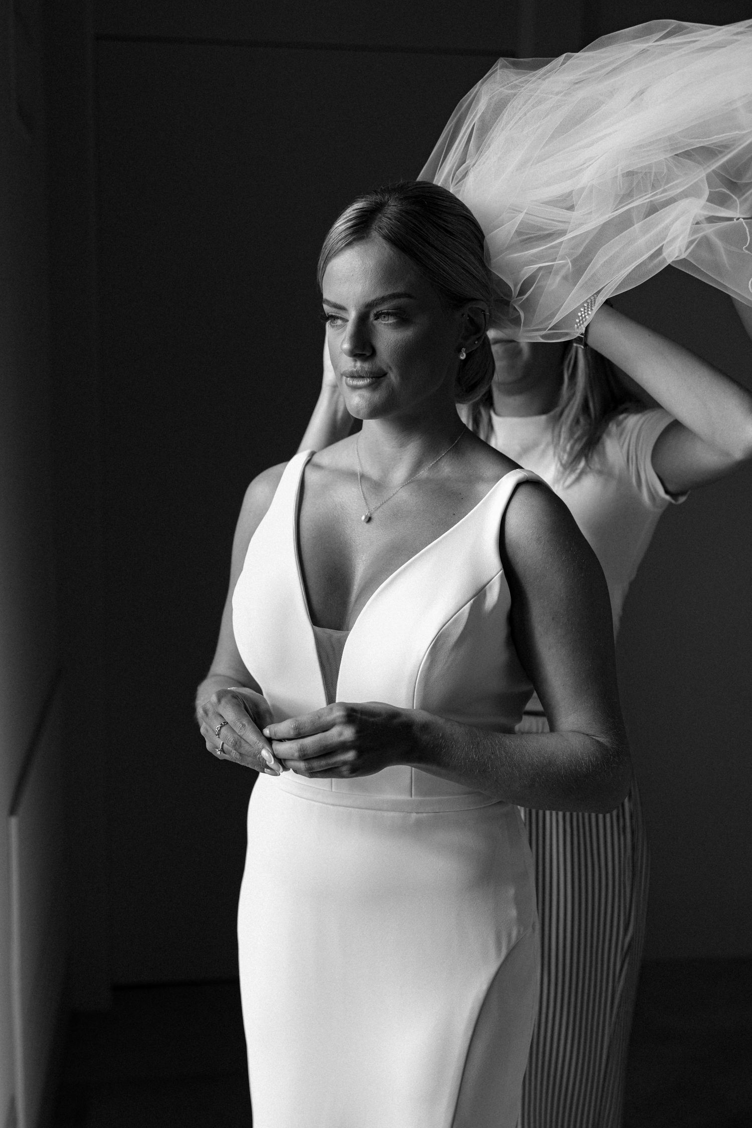 A flowing white wedding veil catches the breeze in an artistic black and white bridal portrait series.
