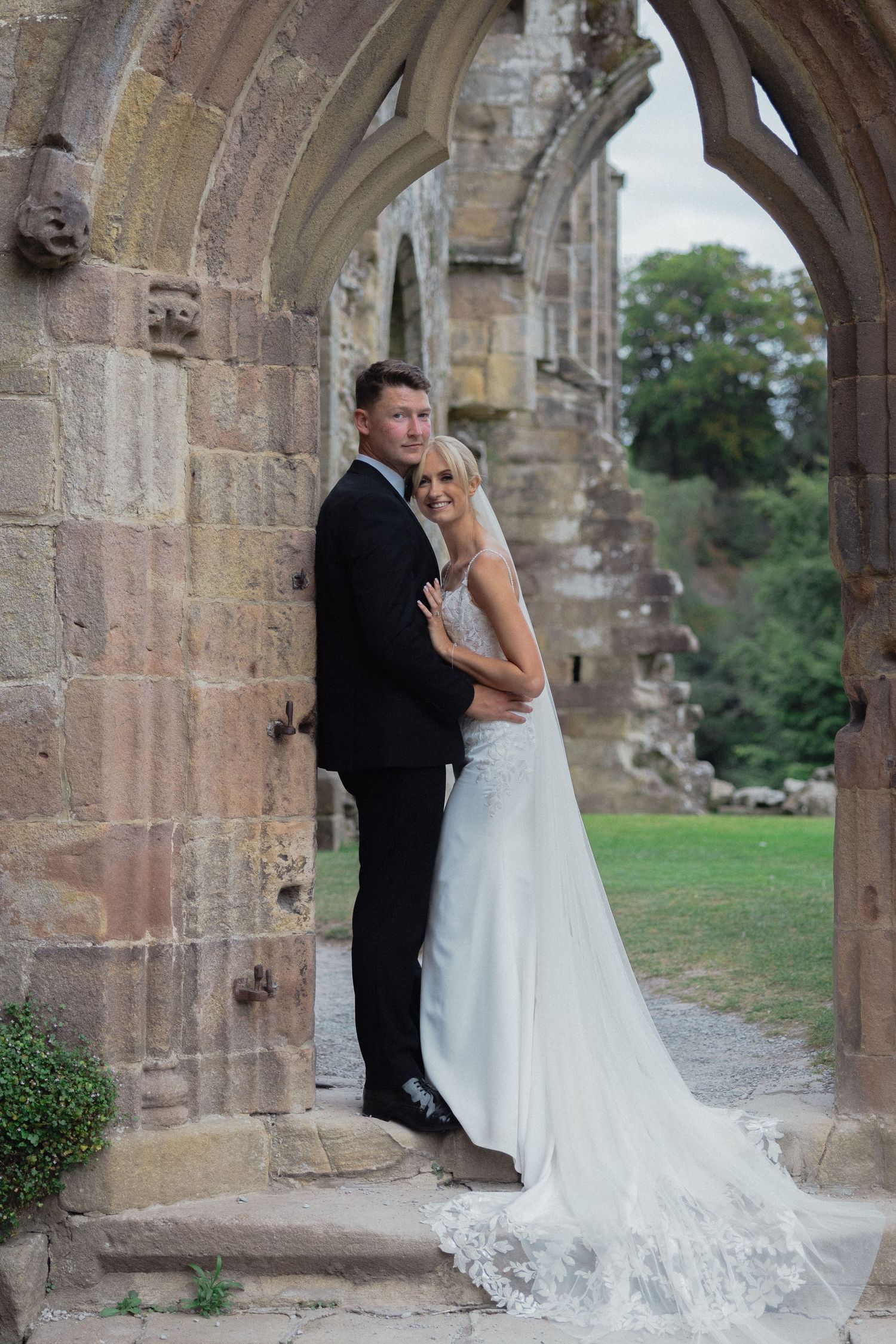 Newlyweds share intimate moments between stone archways of historic ruins.