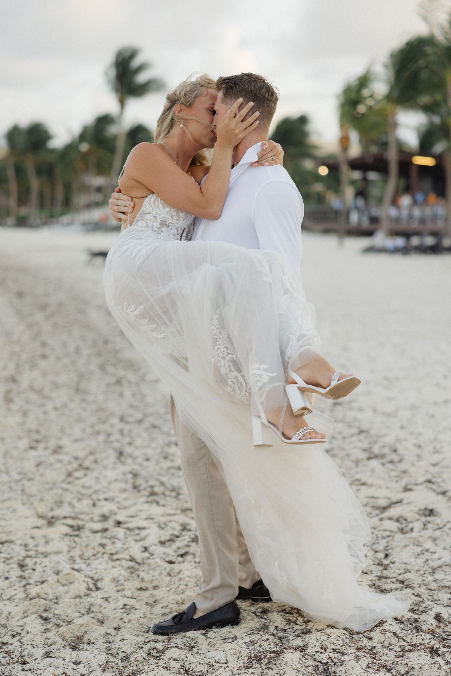 Dramatic beach wedding poses show couple sharing intimate moments with flowing dress movement.
