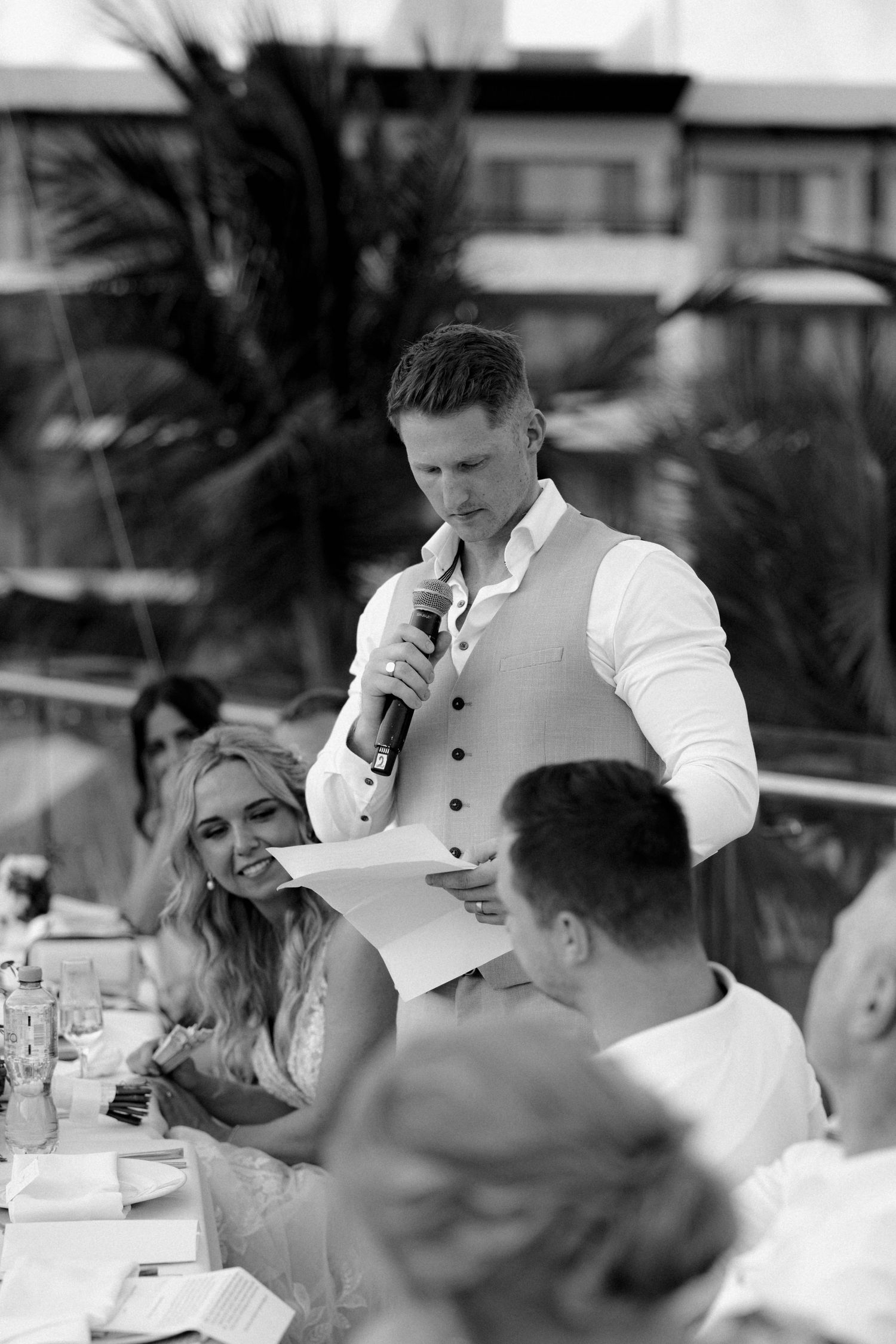 Black and white photo of guests enjoying speeches during a wedding reception.