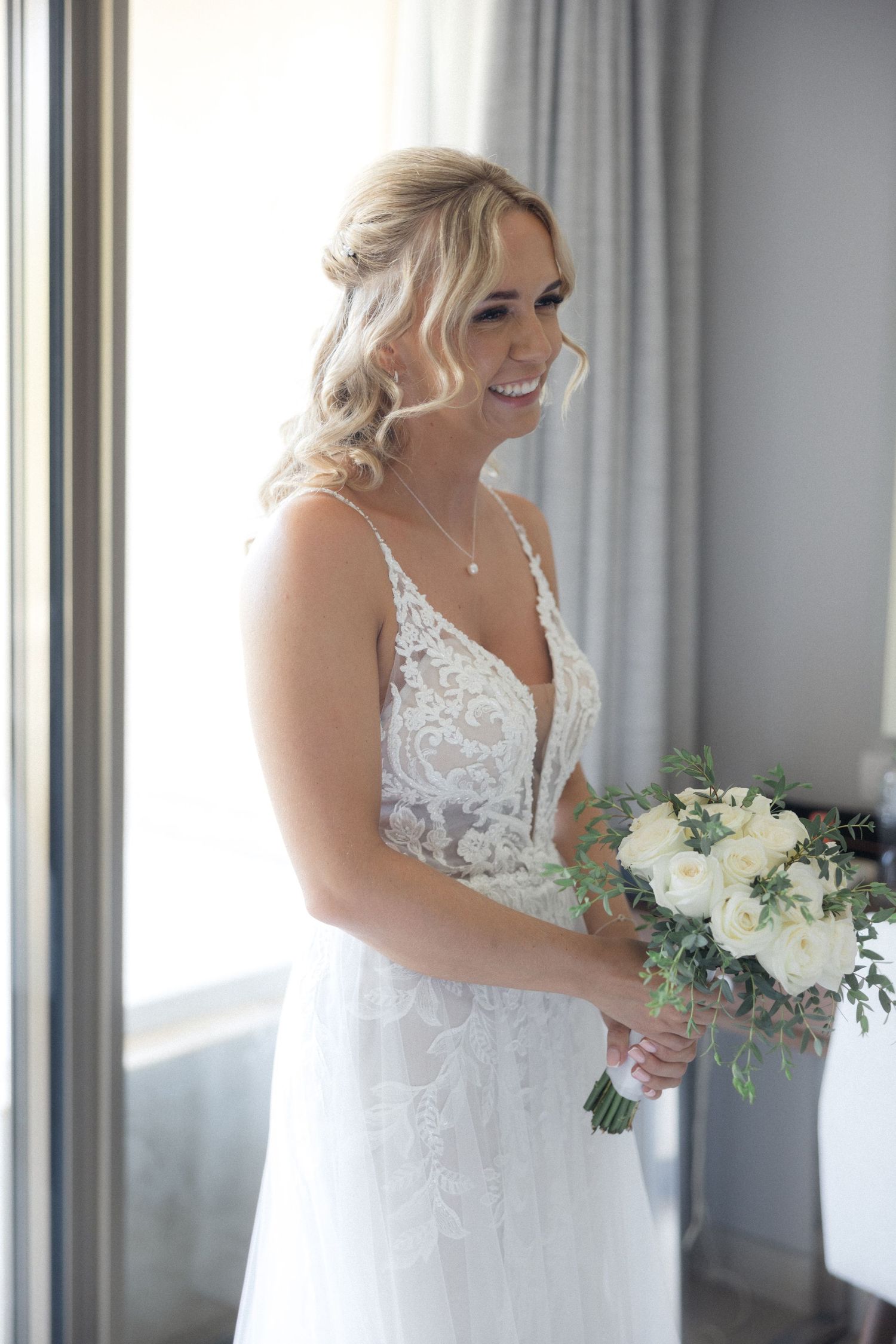 Candid shots of a bride holding a white bouquet while laughing in natural window light.