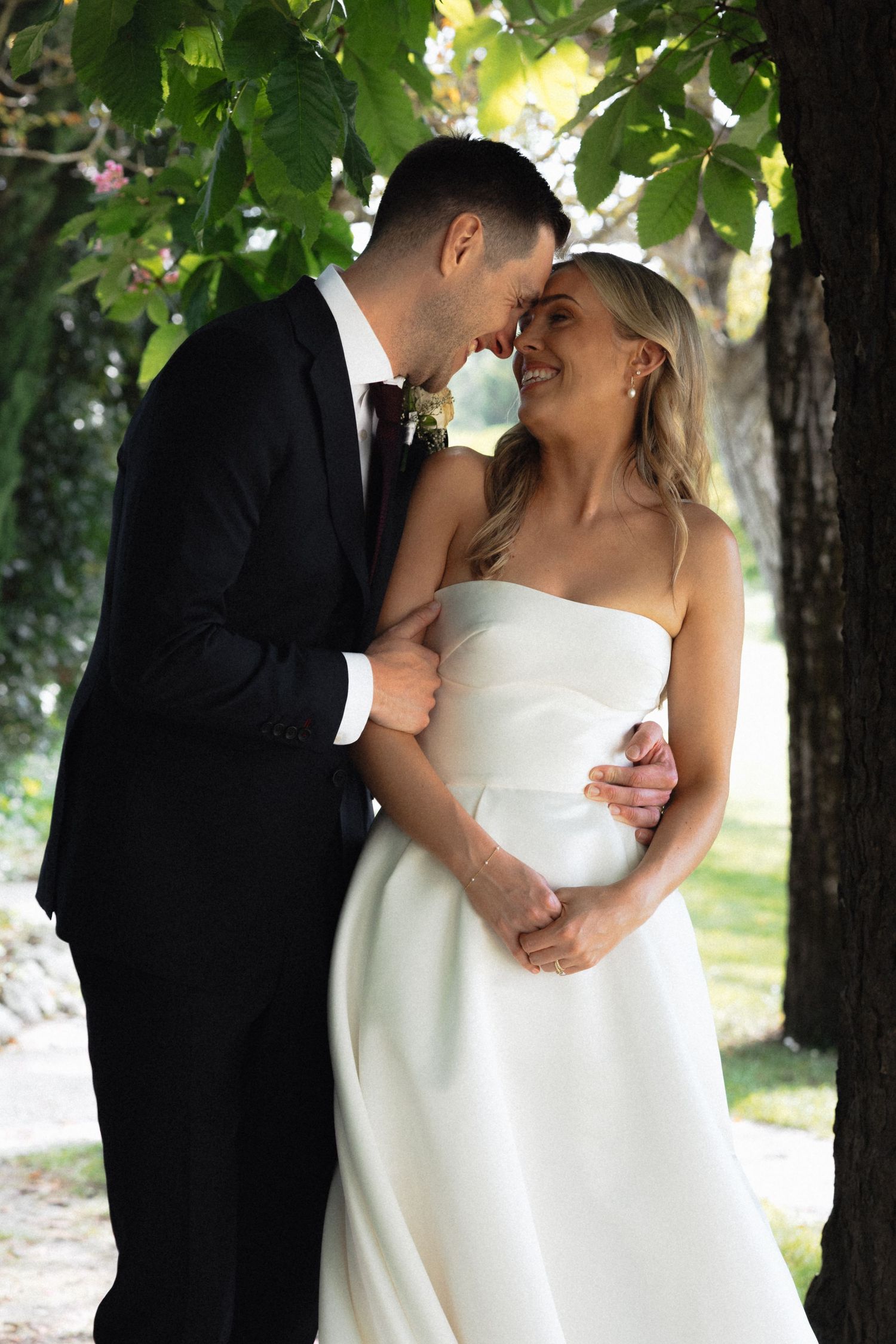 Romantic wedding portraits captured under green tree canopy.