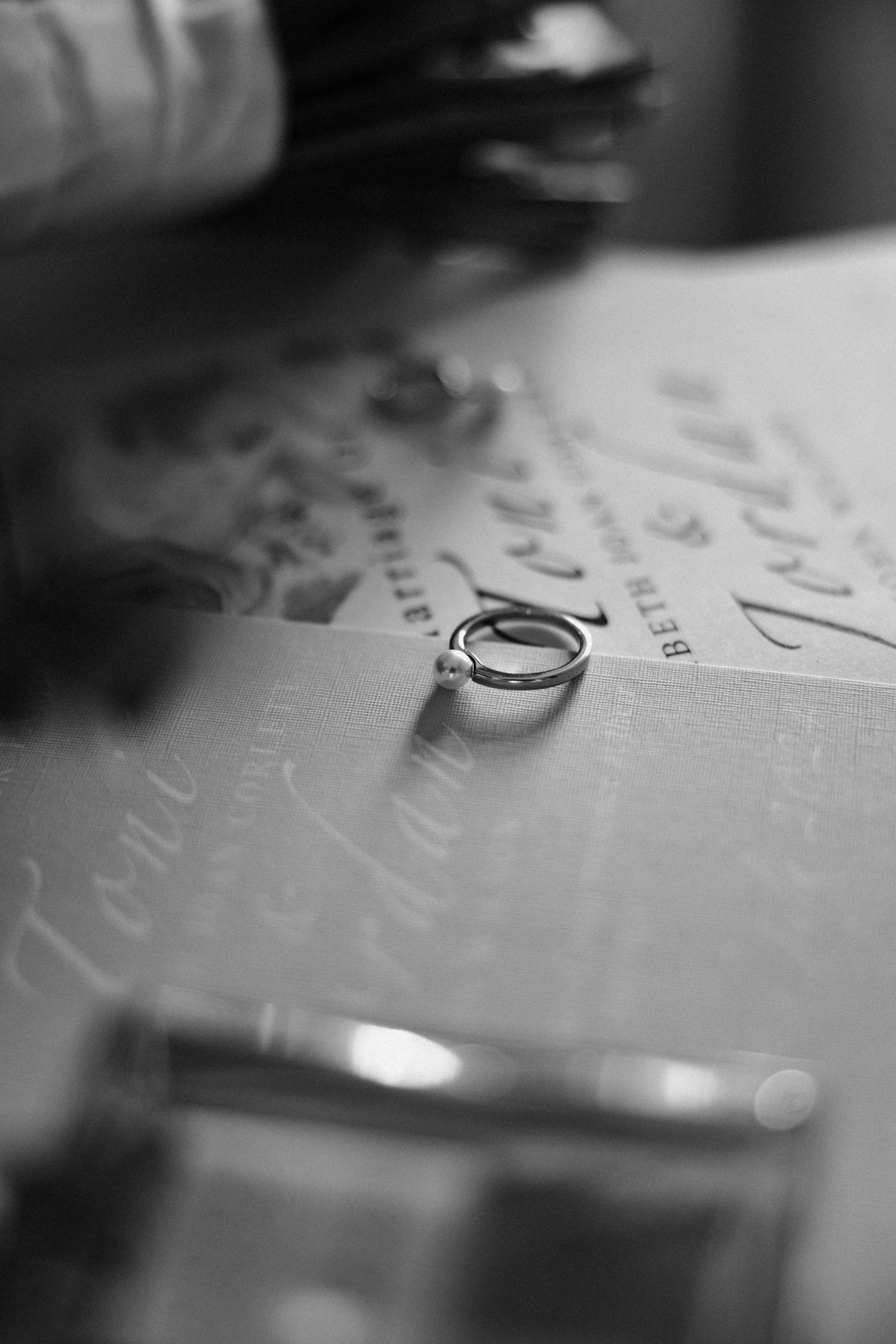 Close-up black and white photo of wedding rings on textured paper.