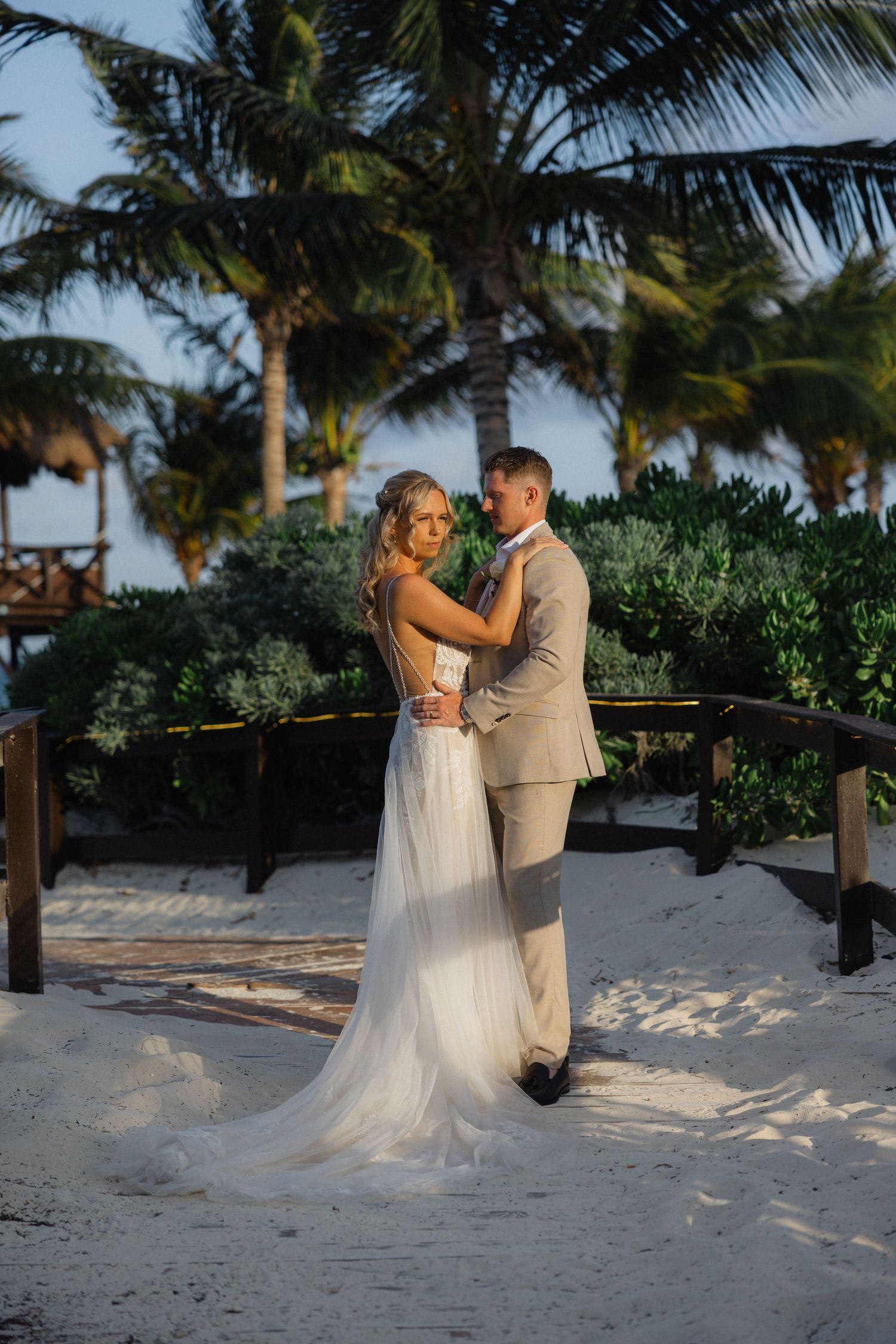 Couple shares romantic moment on tropical beach with palm trees at sunset.