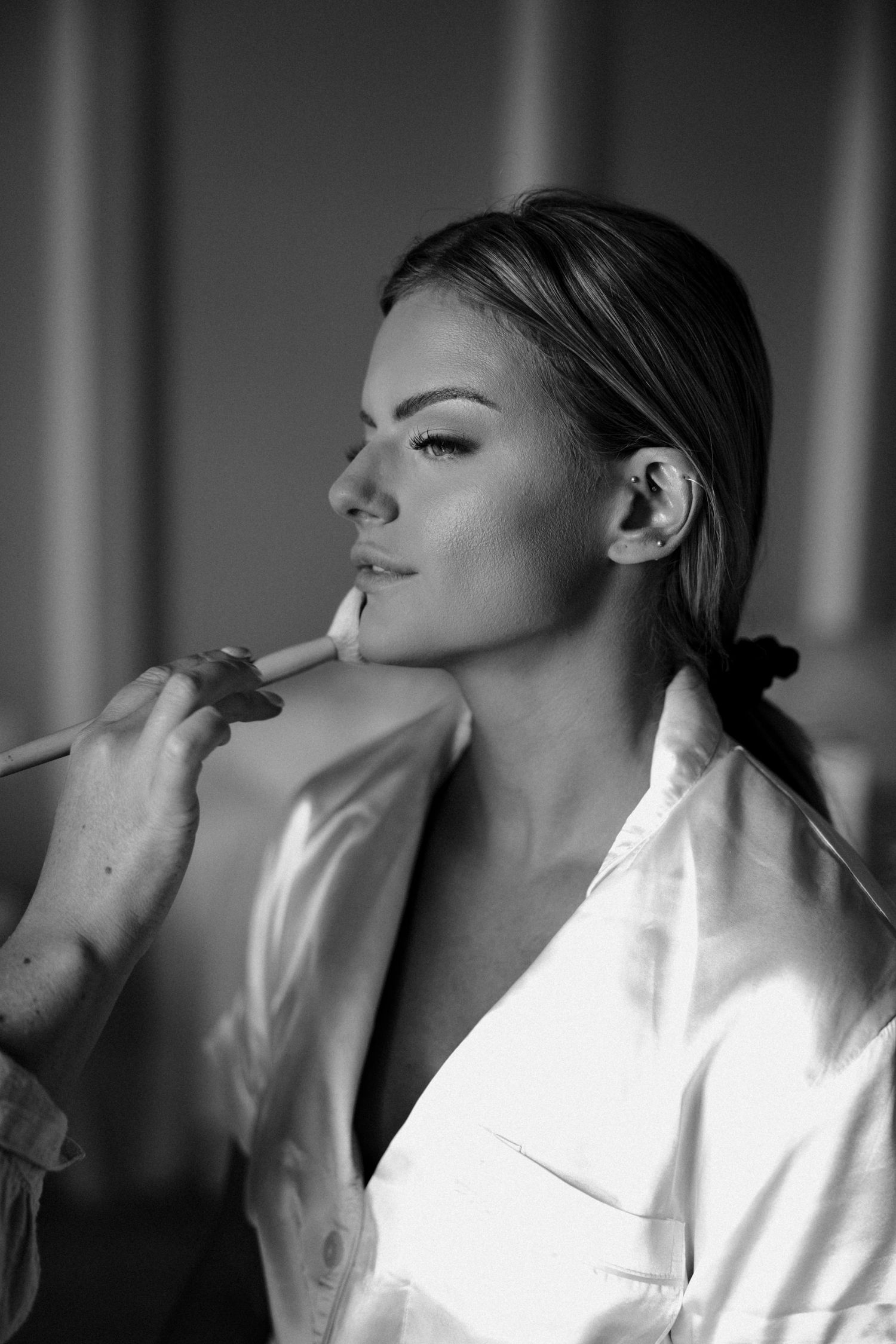 Black and white portrait showing makeup application in profile view.