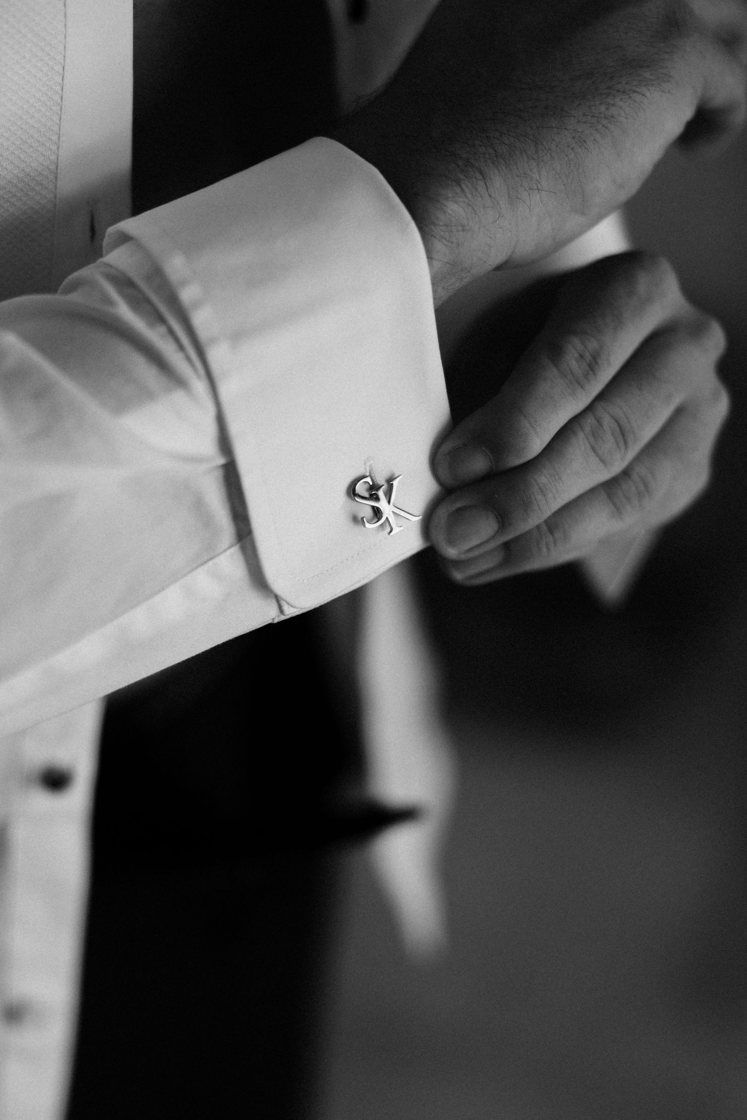 Close-up black and white detail shots of adjusting white shirt cuffs and buttons.