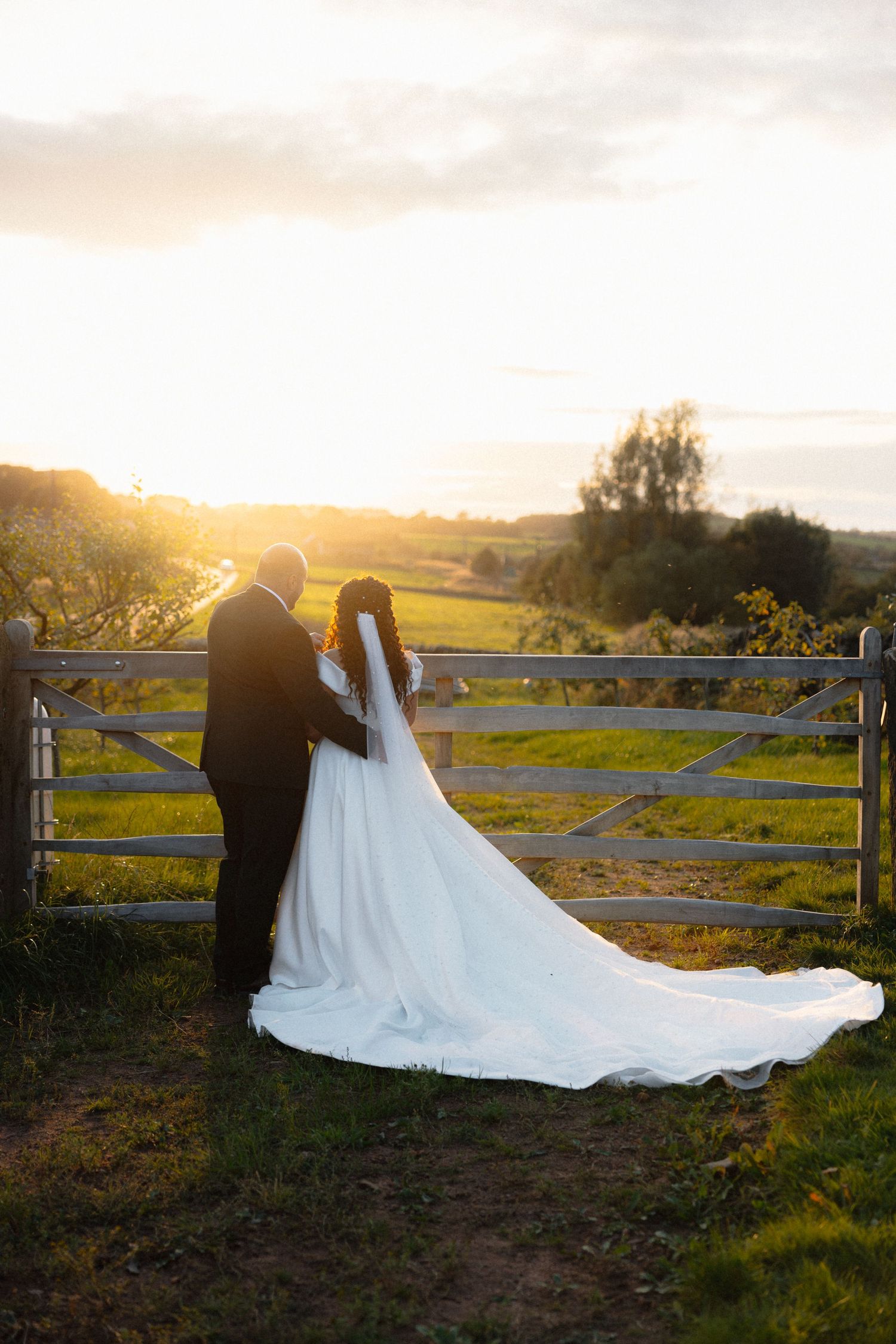 A romantic sunset wedding photo series with a couple silhouetted against a rustic fence.
