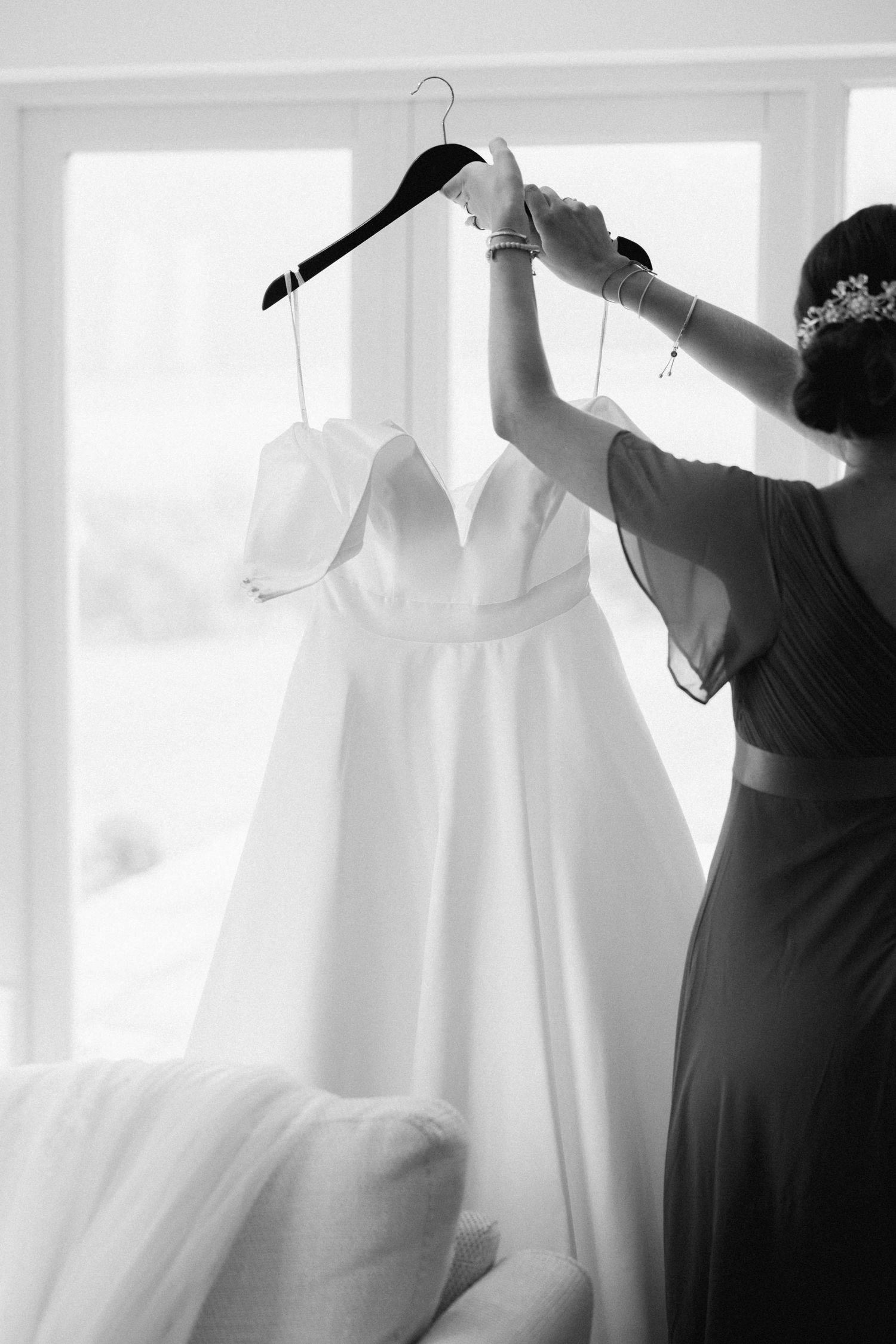 White wedding dress hanging in bright sunlit room with window.