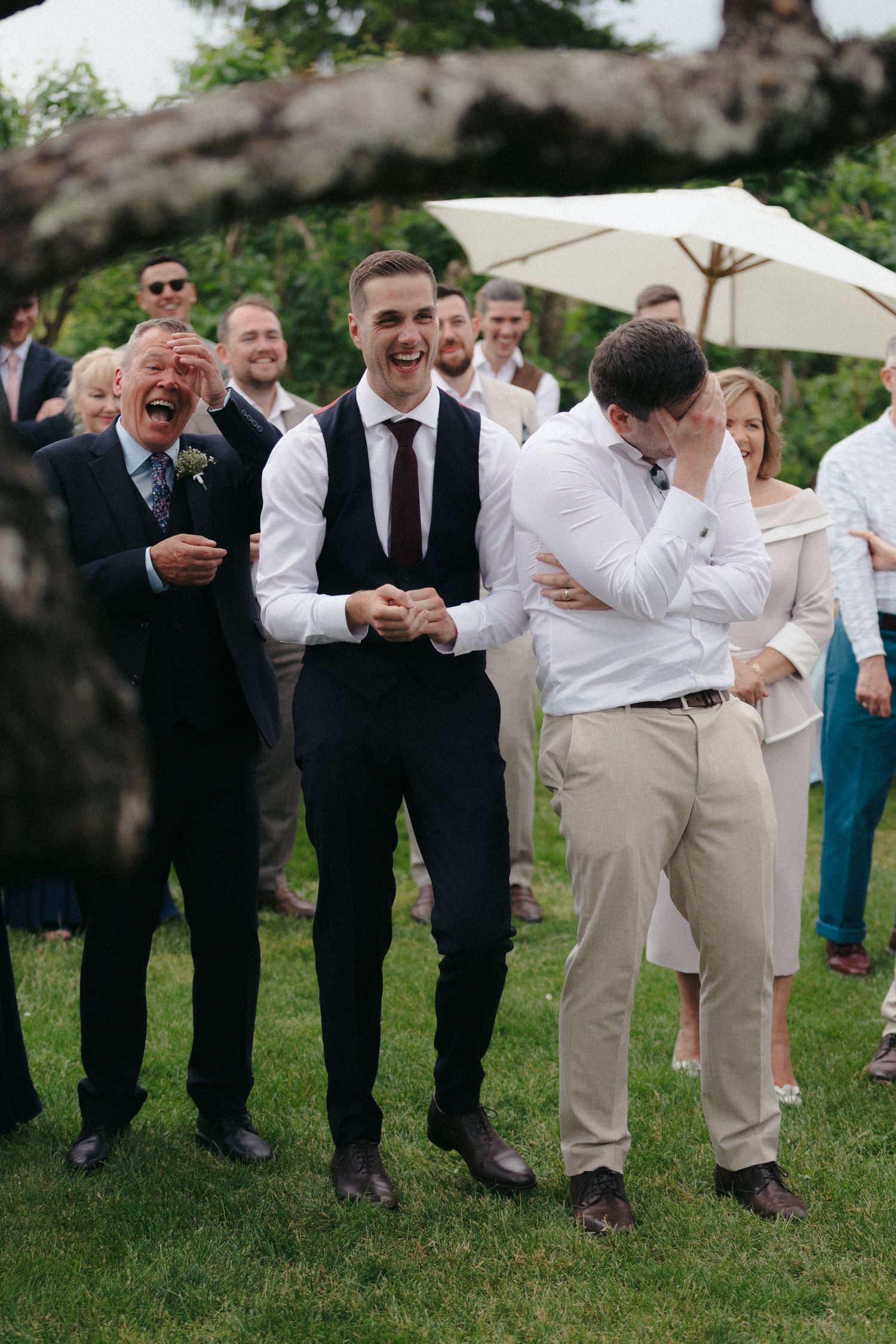 Wedding guests laugh and celebrate during an outdoor reception.