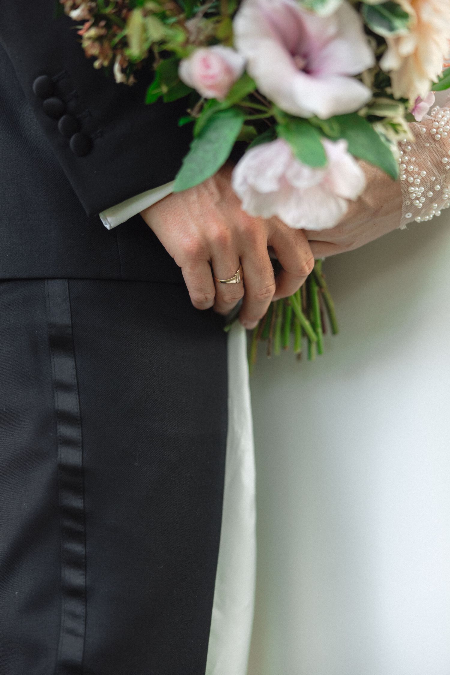 Detail shot of wedding bouquet with pink and white flowers against white dress.