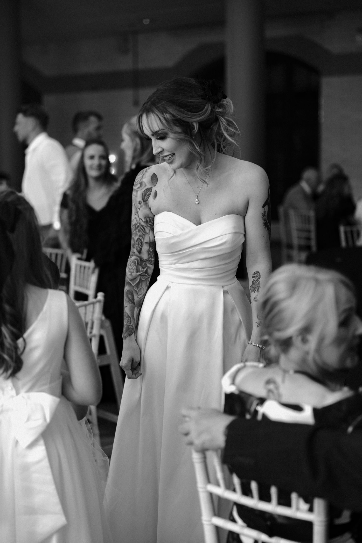 A bride in a classic white wedding dress stands elegantly in an indoor venue.