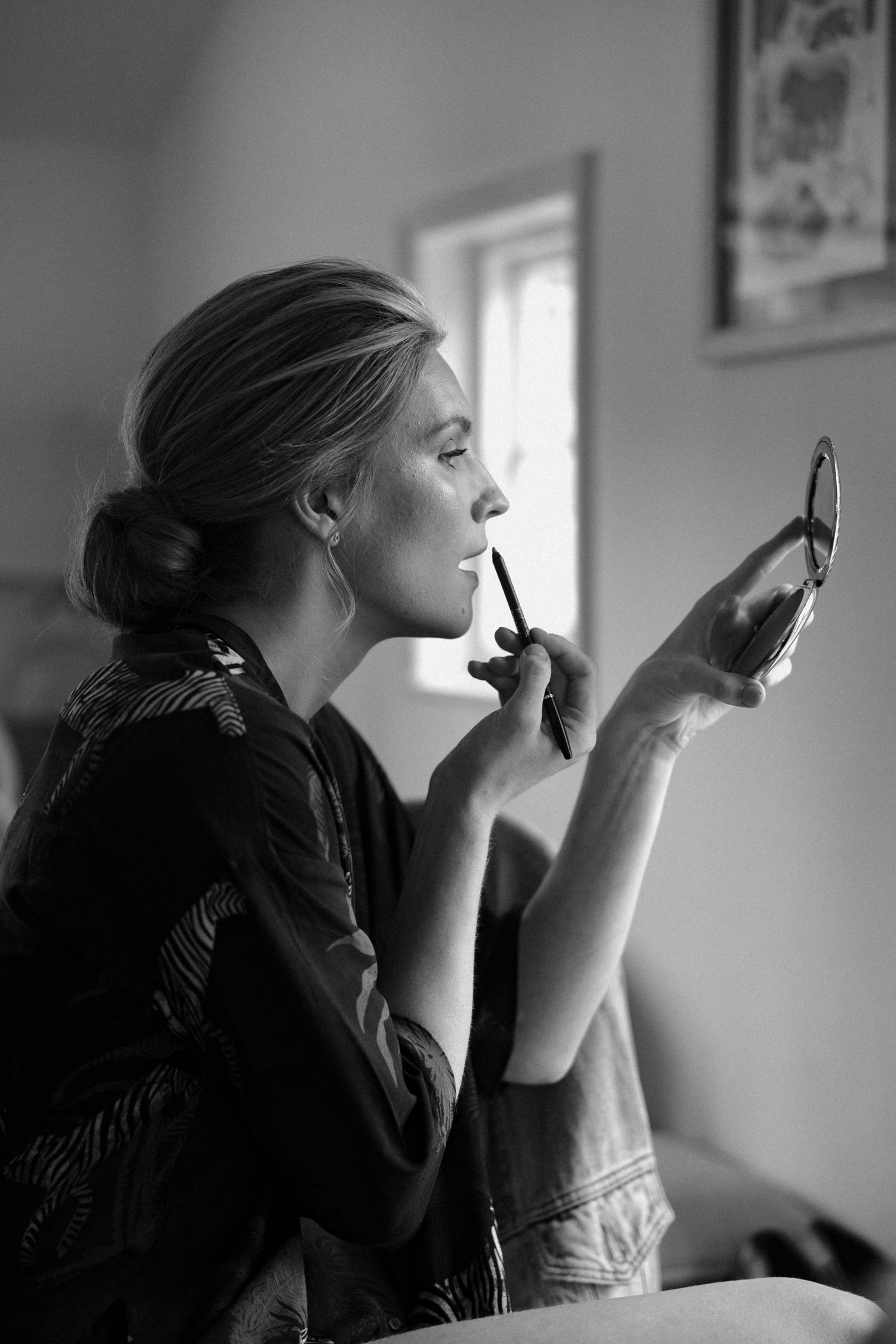Black and white profile shots of woman applying mascara in natural window light.