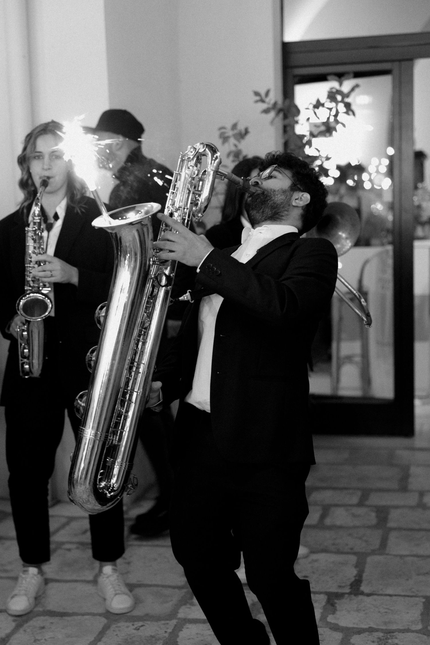 A line of musicians playing saxophones and brass instruments in formal black attire.